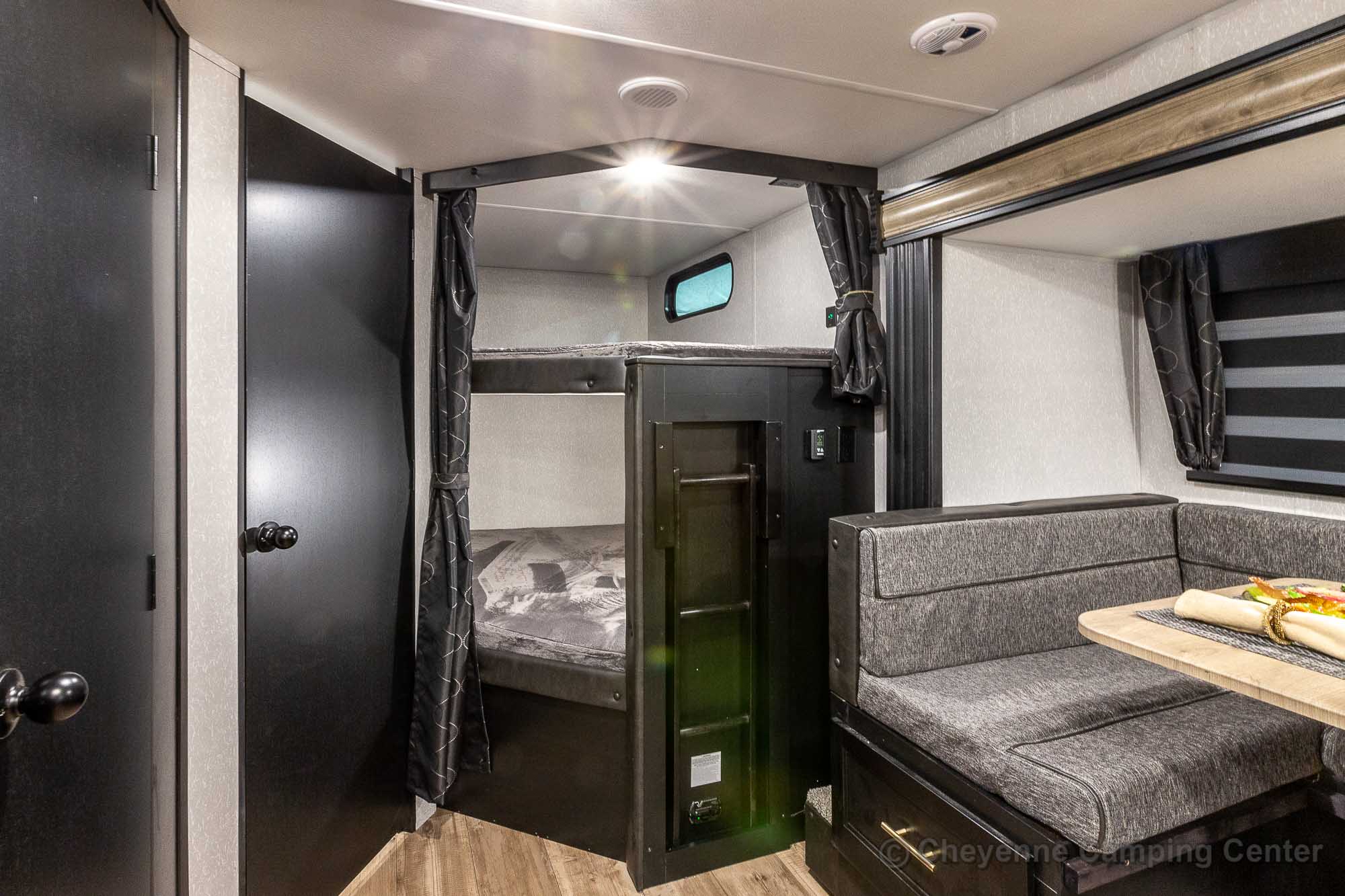 Spacious RV rental interior with cozy dinette and food, bunk beds with privacy curtains, and dark wood doors.. Forest River Cherokee Grey Wolf 2021