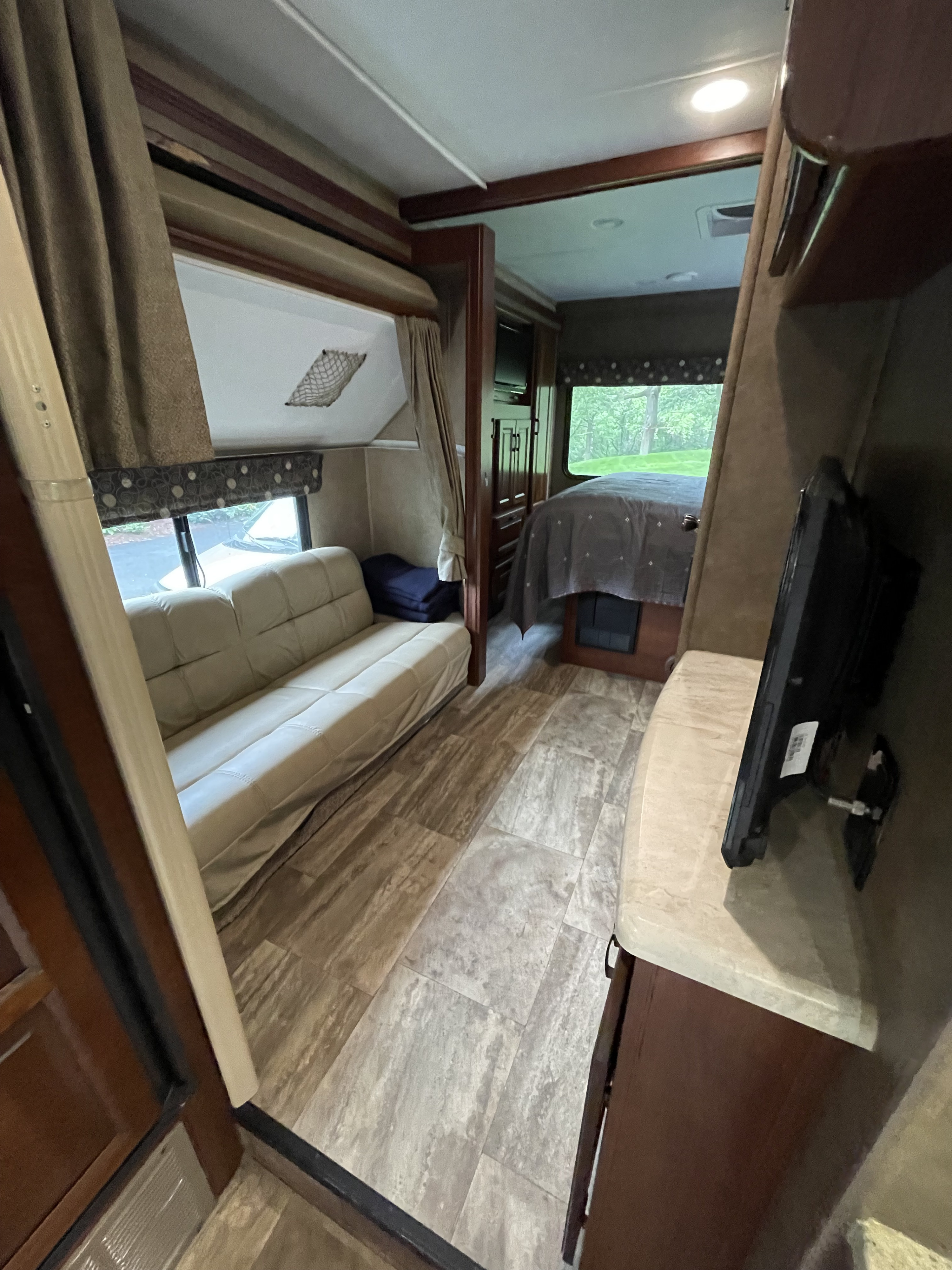 This RV rental offers a comfortable interior with a living area sofa, connected bedroom, TV, and wood-look flooring.. Forester Forester Motorhome 2017