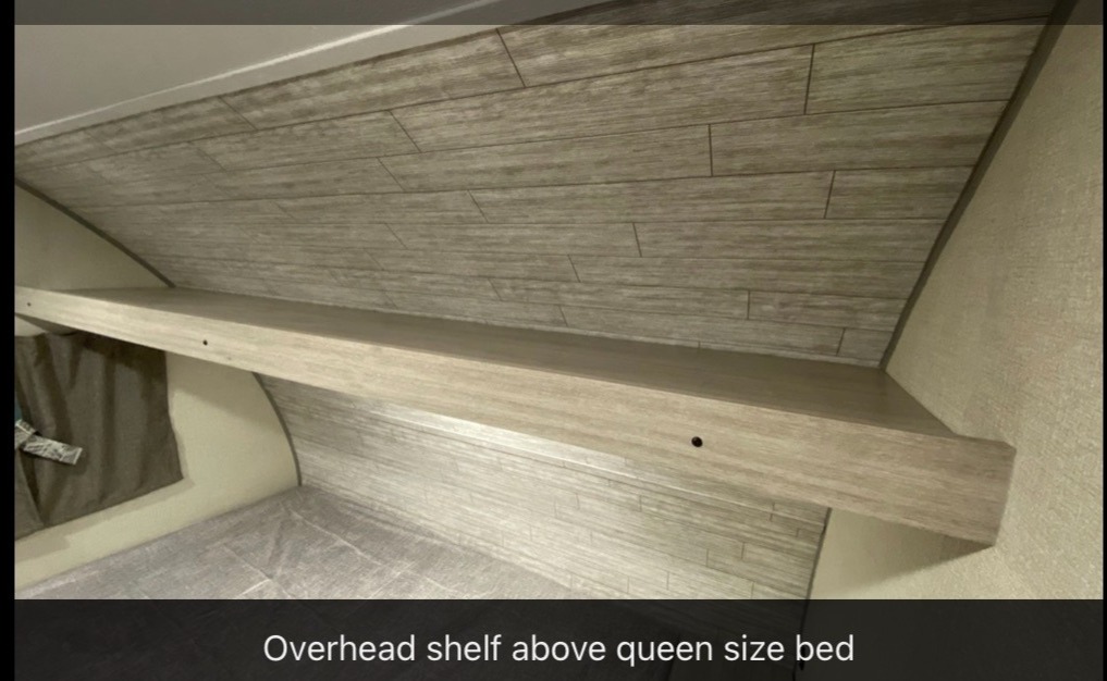 RV rental interior: Light wood overhead shelf above a queen bed for convenient storage.. Forest River Aurora Lite 16BHX 2023