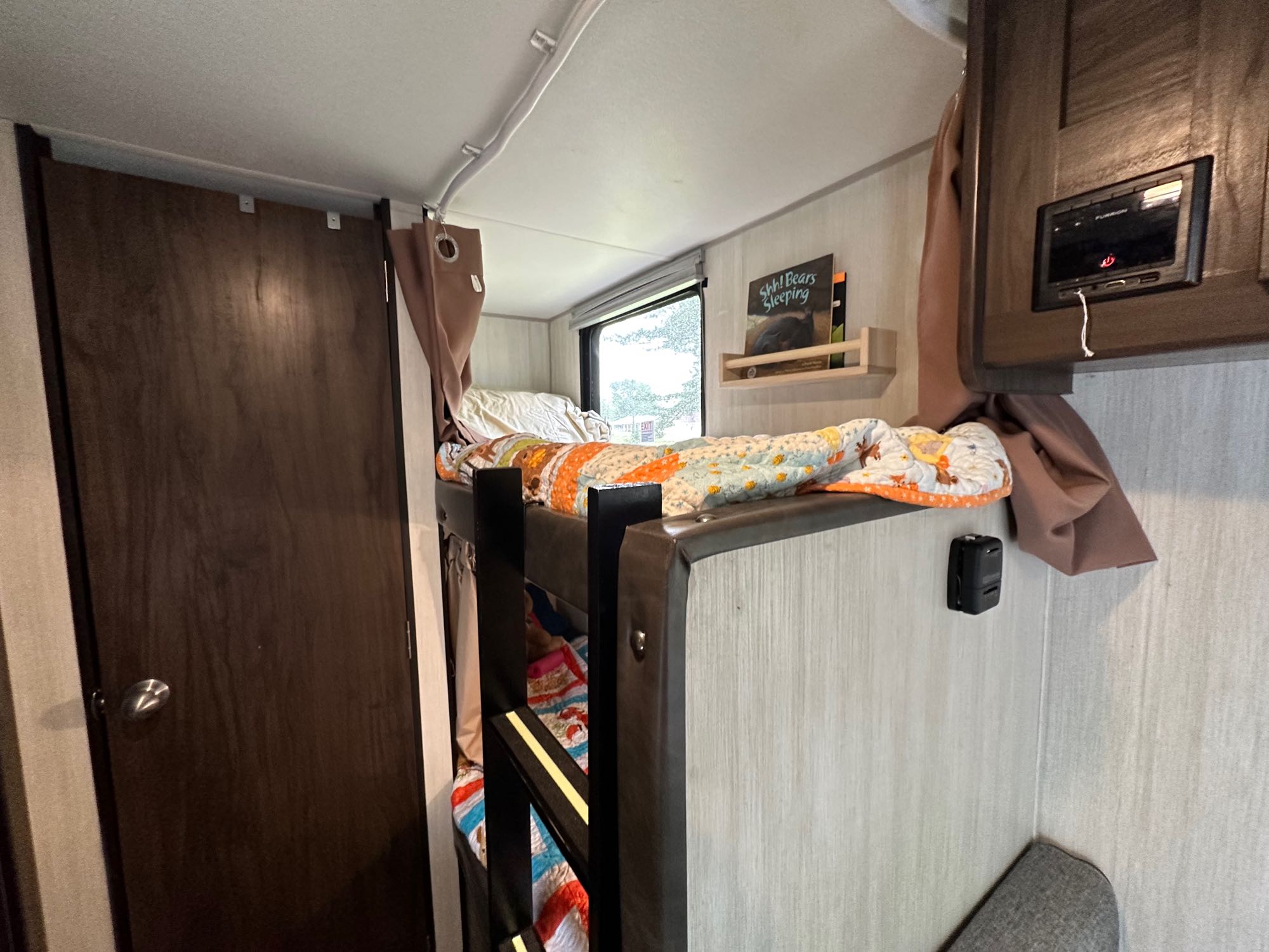 RV rental interior: cozy bunk beds with bedding, a window, control panel, and door. Ideal for family travel.. Forest River Cherokee Wolf Pup 2020