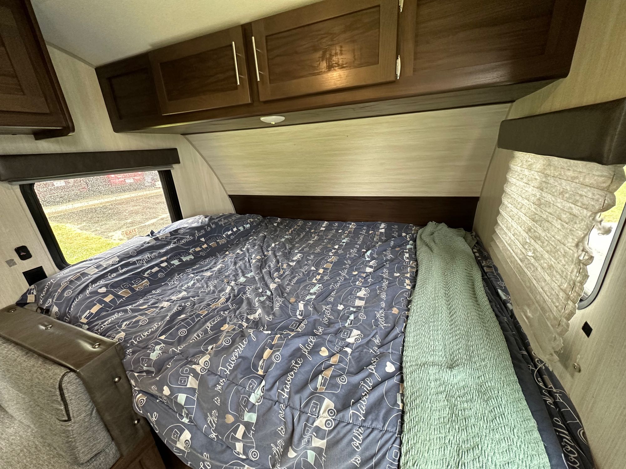 Comfortable RV rental interior: Bedroom with patterned bed, green blanket, and practical overhead storage.. Forest River Cherokee Wolf Pup 2020