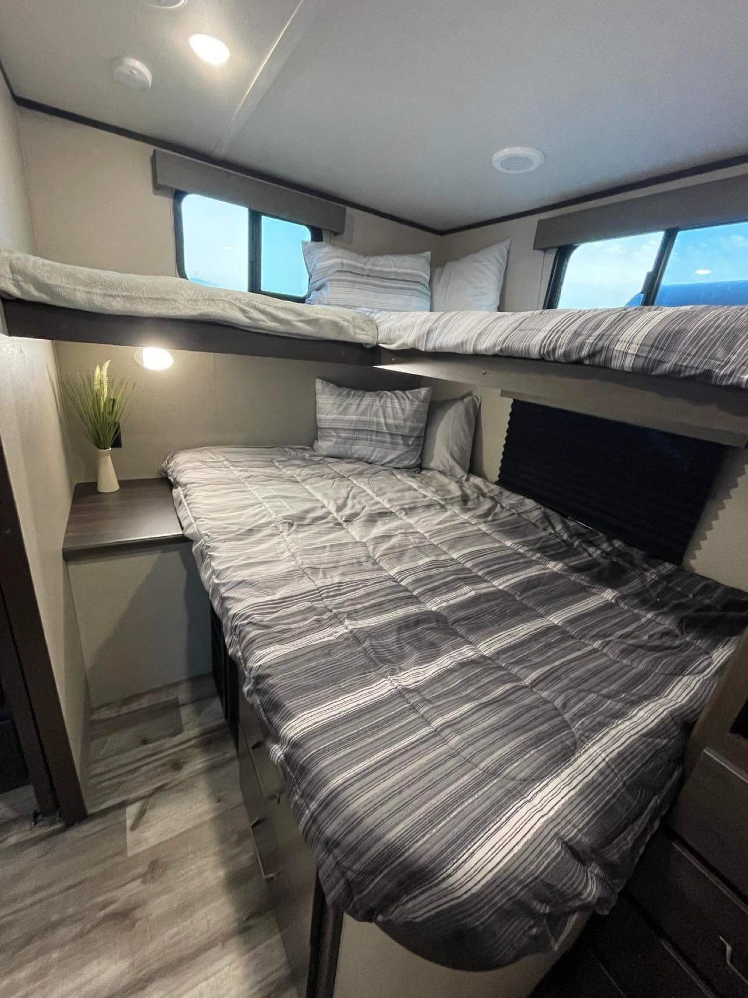 Cozy RV rental bunk beds, perfect for family travel. Features window views, overhead lighting, and compact storage.. Grand Design Transcend Xplor 2023