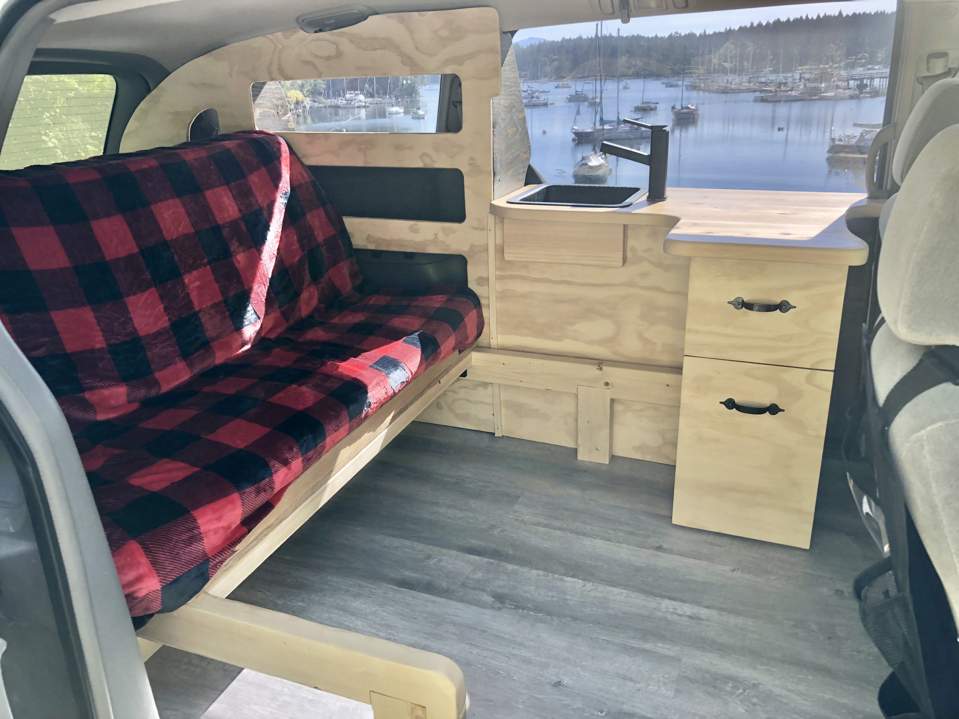 This RV rental features a cozy bed, mini kitchen with sink, and scenic harbor views from its converted interior.. Toyota Hiace 2007