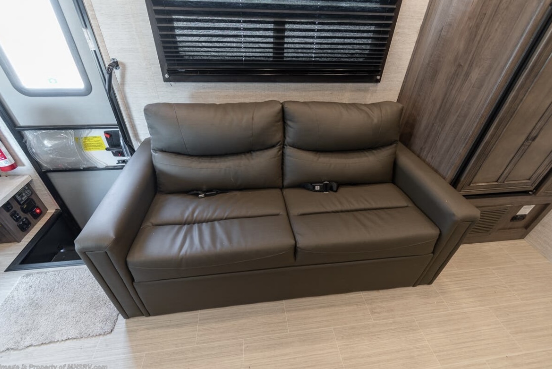 This RV rental features a comfortable two-seater sofa, entry door, & cabinetry. Ideal for compact travel.. Entegra Coach Odyssey 2022