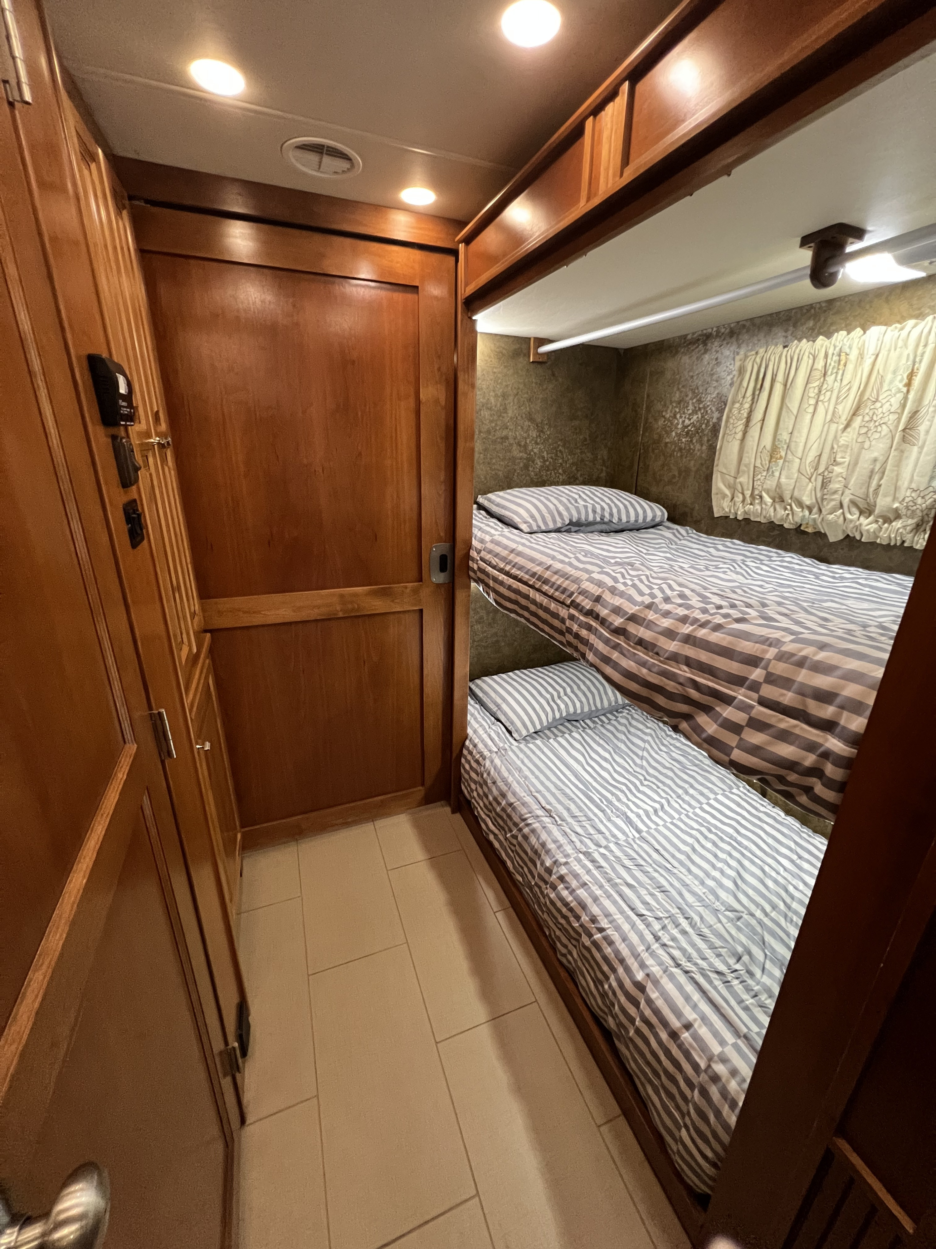 RV rental interior featuring comfortable bunk beds, wood cabinetry, and a cozy sleeping space.. Tiffin Phaeton 40QKH (Bunkhouse) 2014