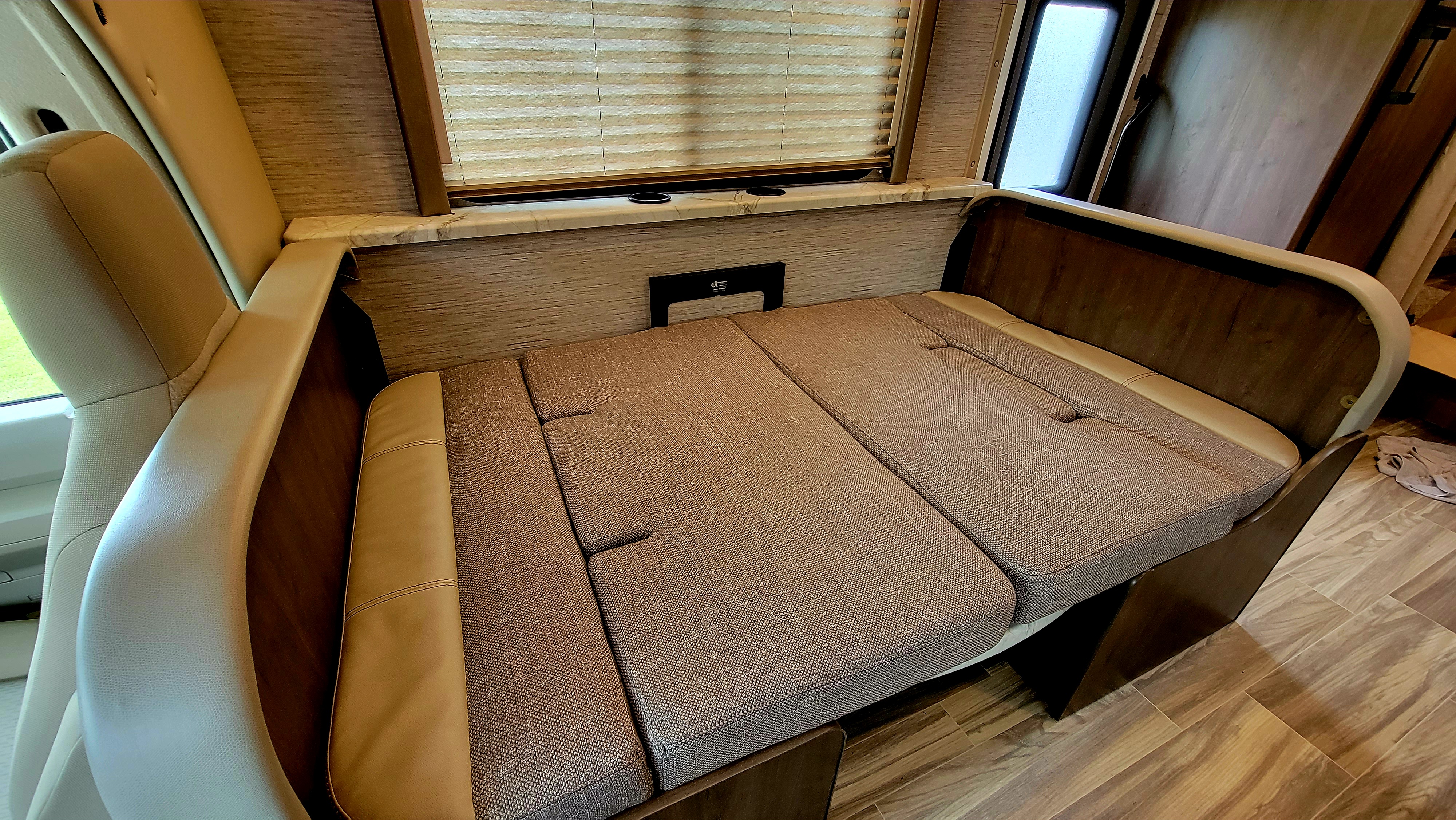 RV rental interior features a versatile dinette that converts into a bed, complete with a window, blinds, and cup holders.. Thor Freedom Elite 2021