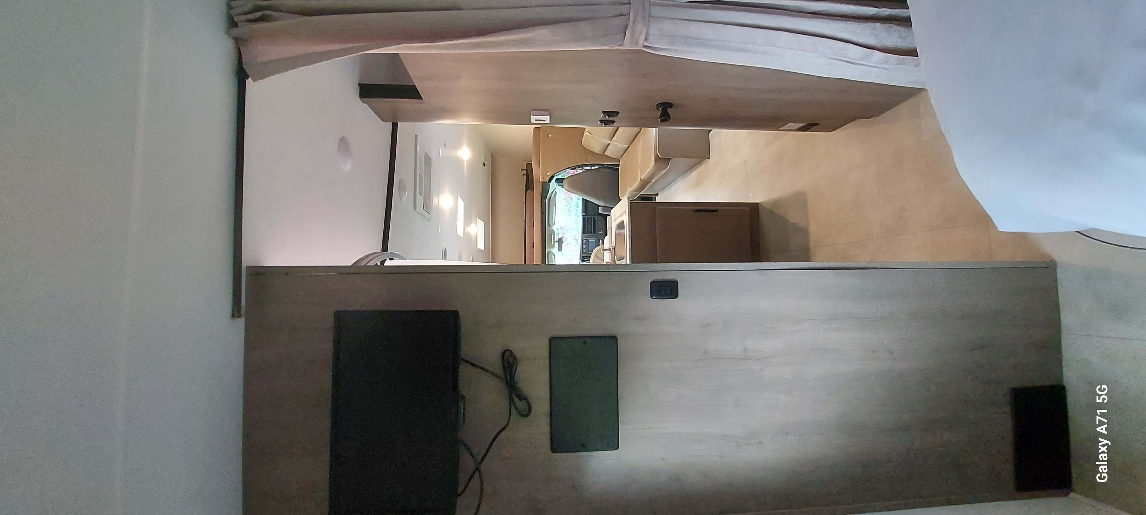 Spacious rv rental interior: modern living area with a TV on counter, comfortable seating, and driver's cab.. Forest River Coachmen Freelander 2021