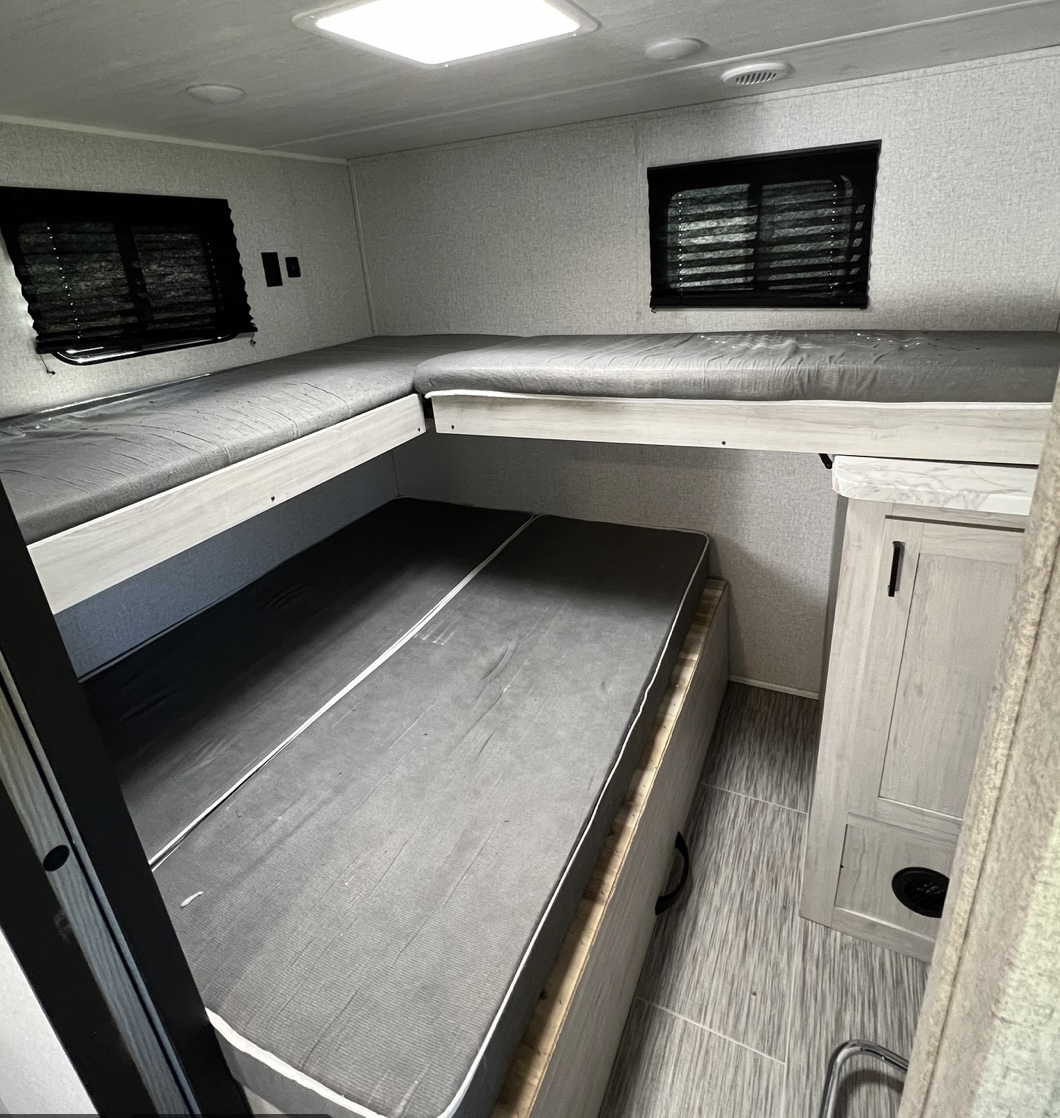 Spacious RV rental sleeping area featuring L-shaped bunk beds and a lower bed, perfect for families.. East to West Silver Lake 2022