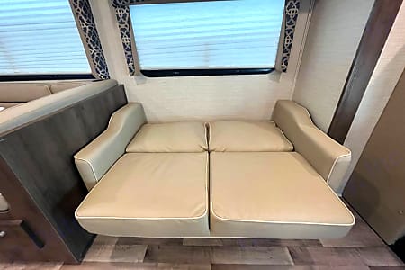 This RV rental features a cozy, light-colored convertible sofa, ready to become a comfortable bed for your travels.. Jayco Redhawk 2021