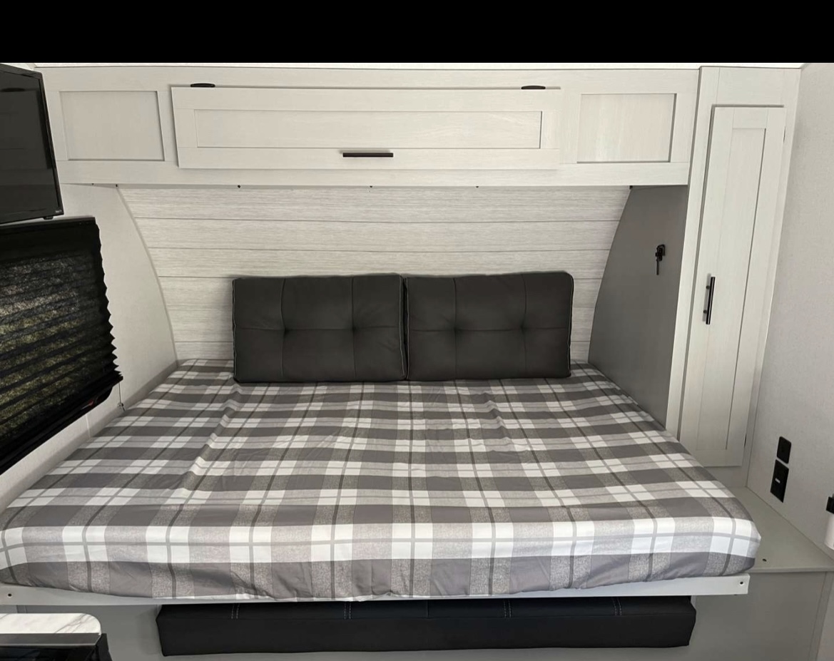 Your cozy RV rental bedroom awaits! Features plaid bedding, overhead cabinets, and smart storage for comfortable travel.. Forest River Salem FSX 2021