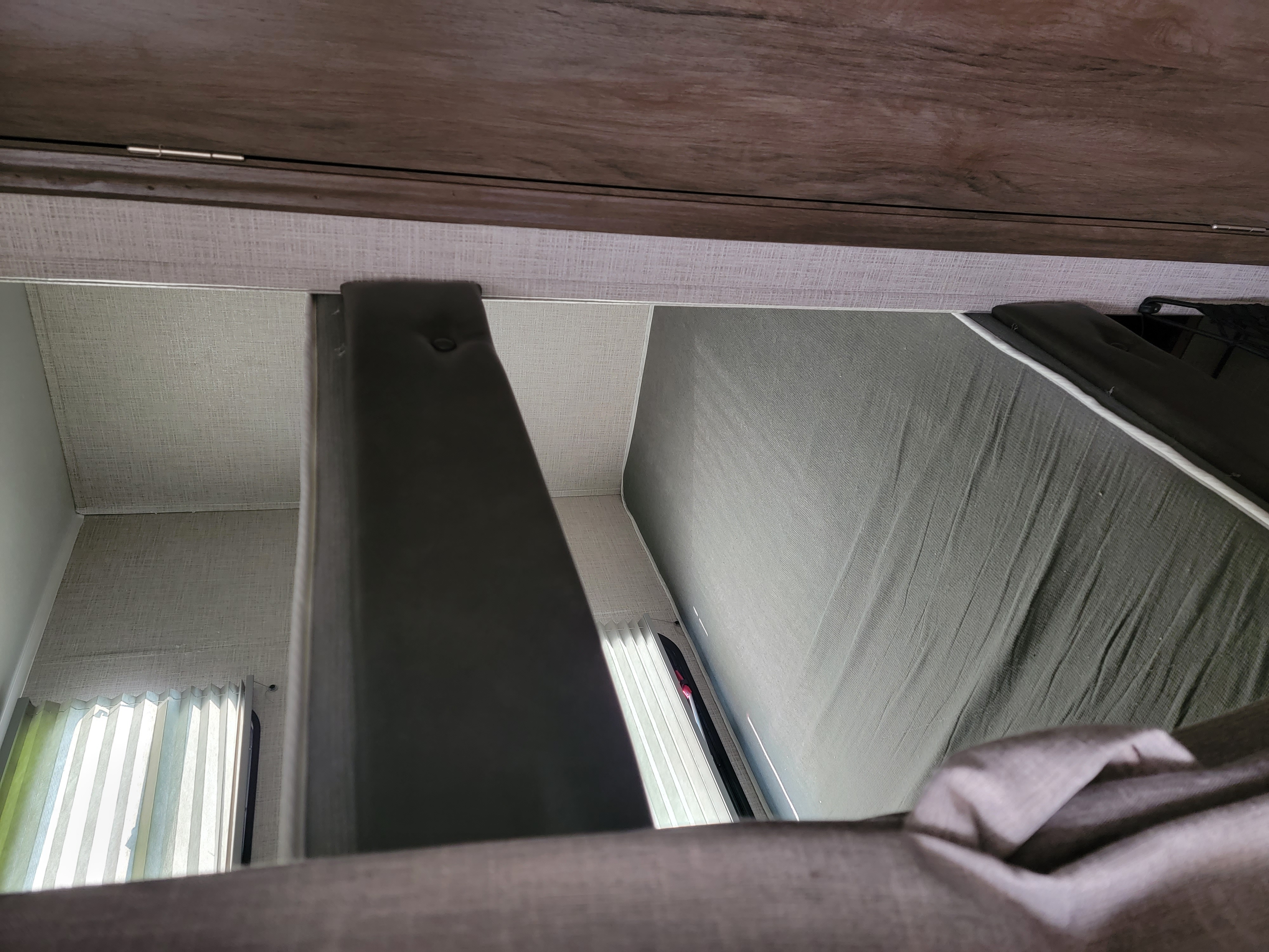 RV rental: View from below an RV bunk bed, showing the mattress, window with blinds, and cabinet overhead.. East to West Della Terra 2021
