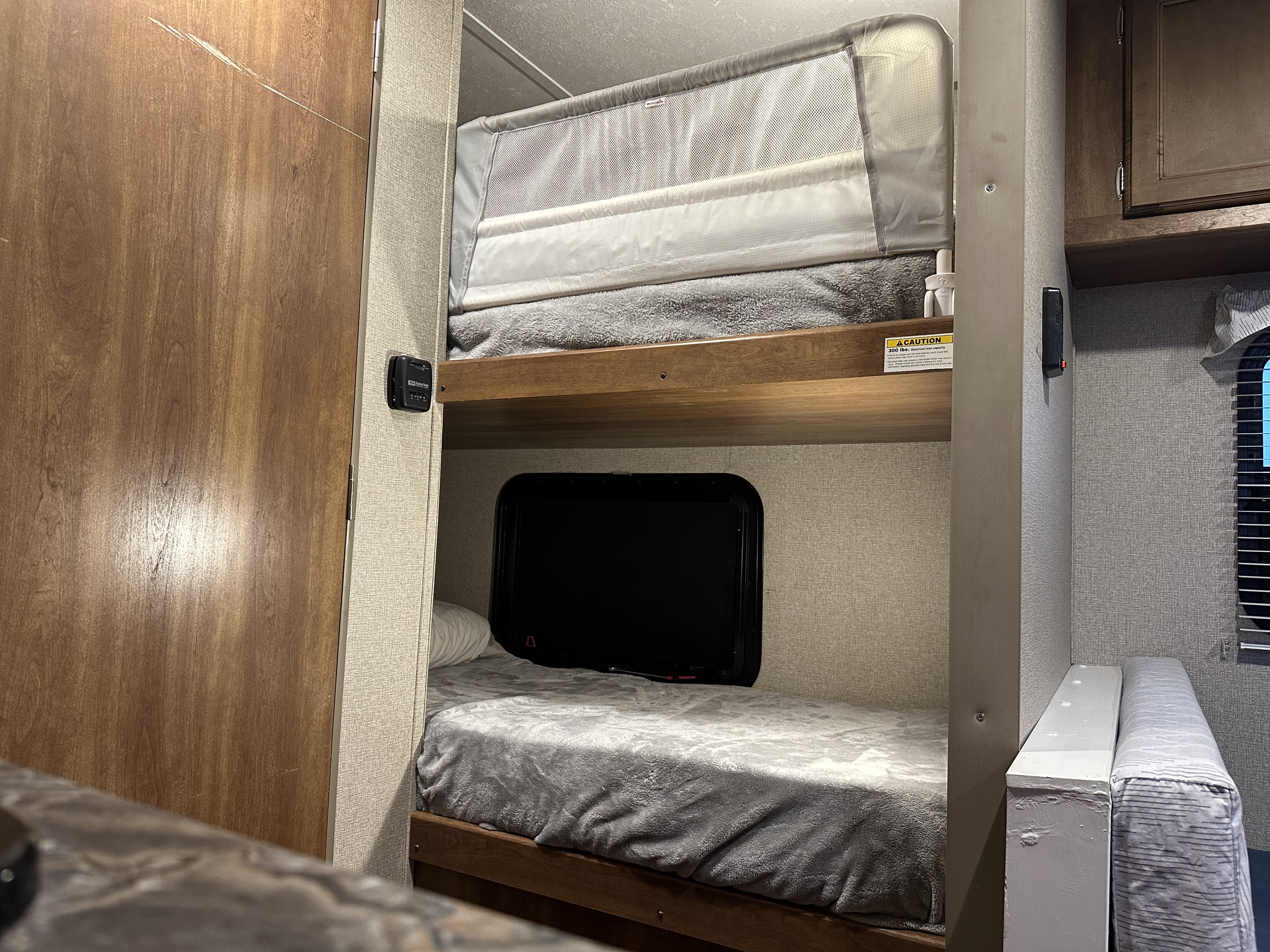RV rental interior with bunk beds, top bunk featuring a safety rail. A cozy sleeping area with a window below.. Keystone RV Summerland Mini 2017