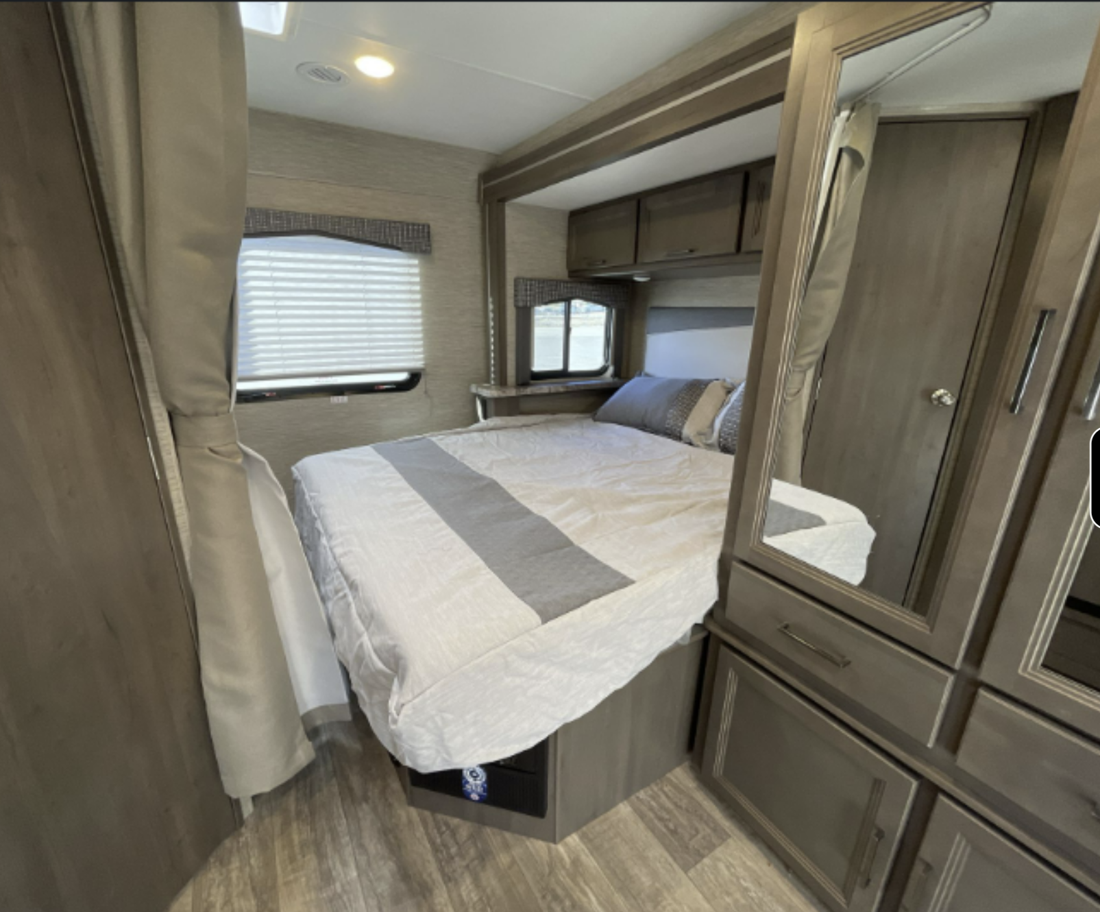 This RV rental bedroom features a comfortable bed, storage cabinets, and windows, offering a cozy retreat on wheels.. Thor Chateau 2023