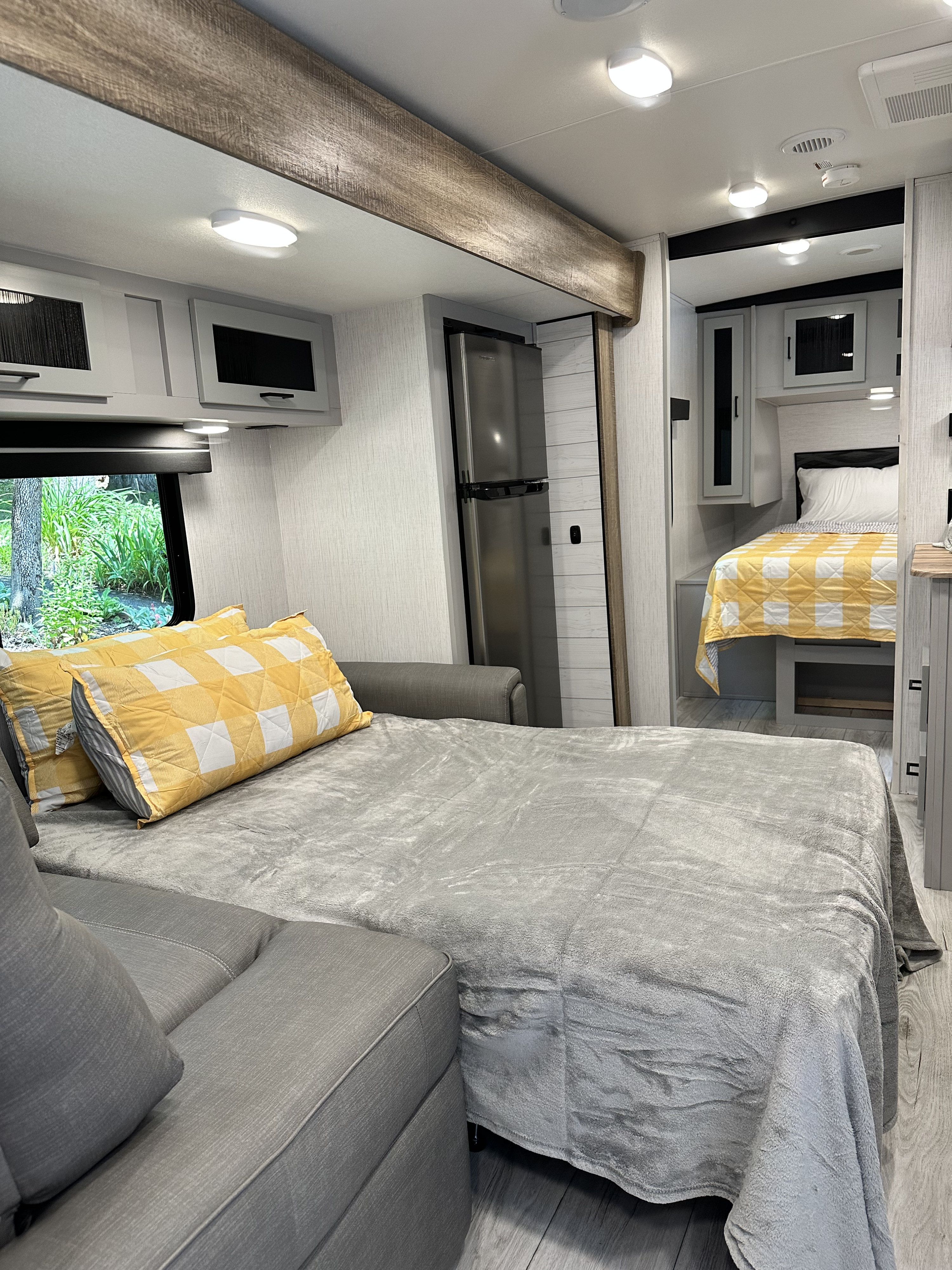 Bright, modern RV rental interior with a comfy convertible sofa bed, full bedroom, and stylish wood accents.. Heartland RVs North Trail 2022