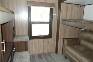 RV rental bunkhouse interior: Cozy space with bunk beds over a sofa, a window, and storage cabinets.. Jayco White Hawk 2018