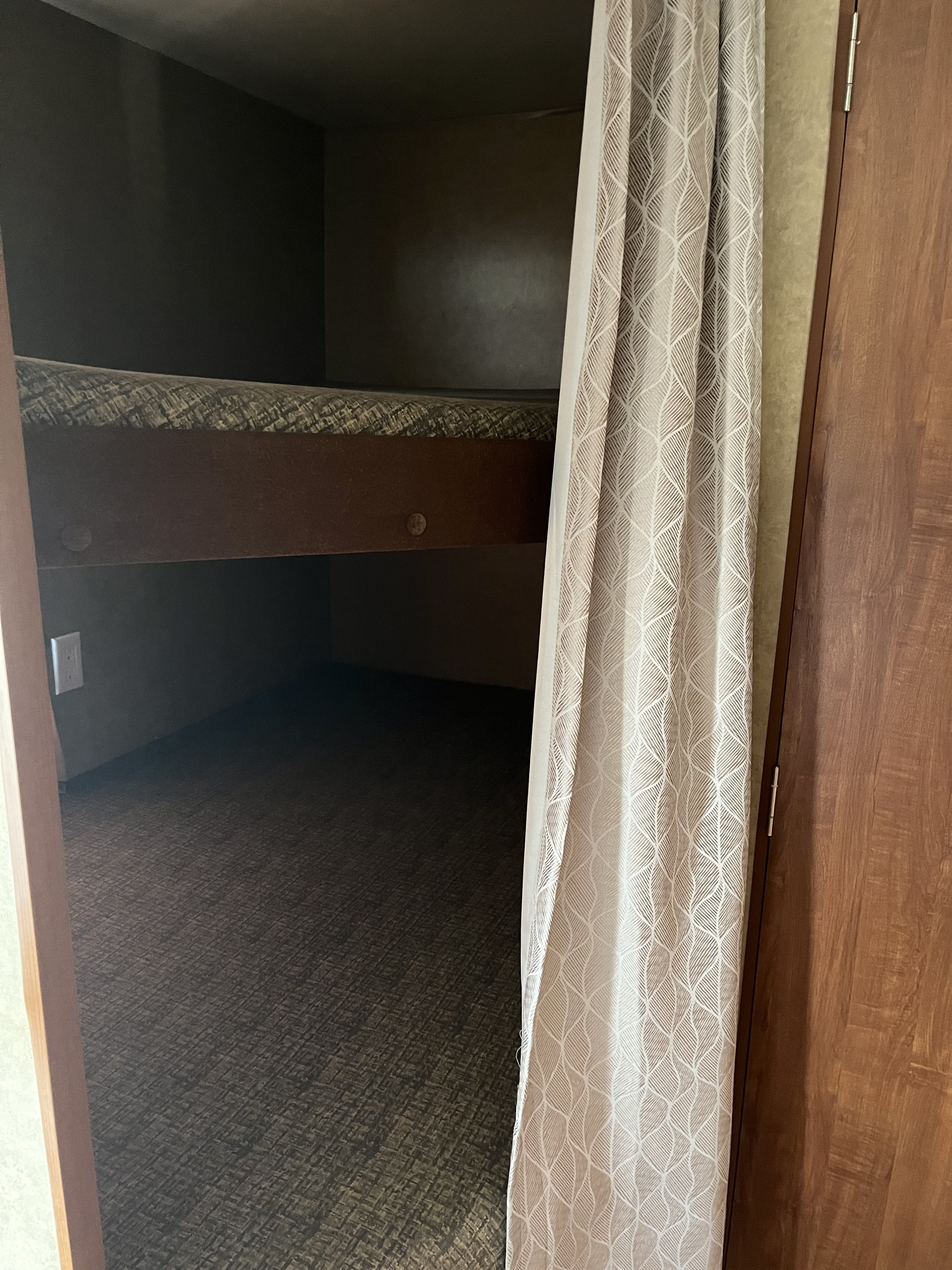 RV rental bunk beds: a compact sleeping space with a top mattress, privacy curtain, and wall outlet visible.. Jayco Jay Flight Swift 2013