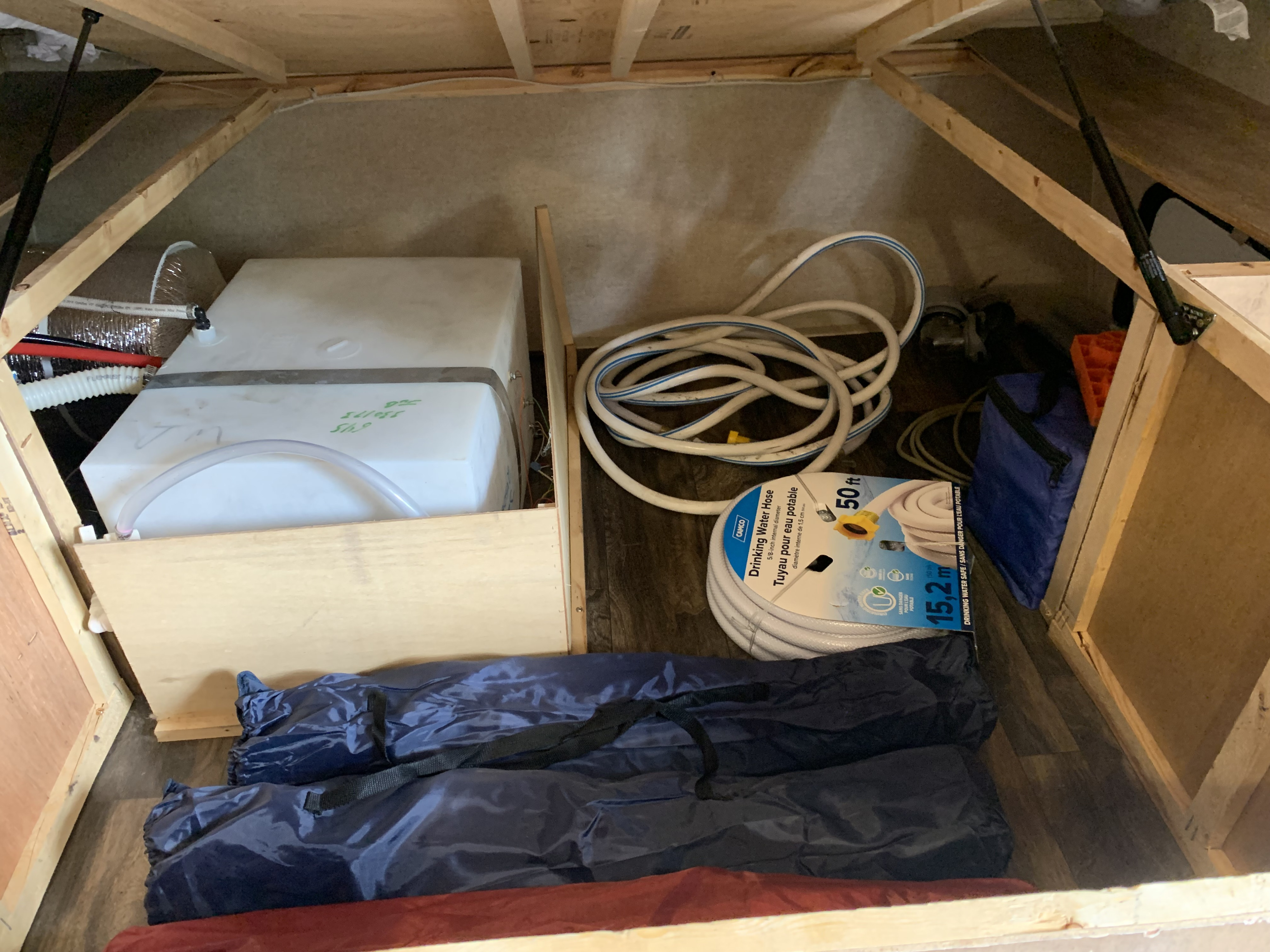 RV rental utility bay showing freshwater tanks, a drinking water hose, and camping gear neatly stored.. Starcraft Launch Outfitter Extreme 2018