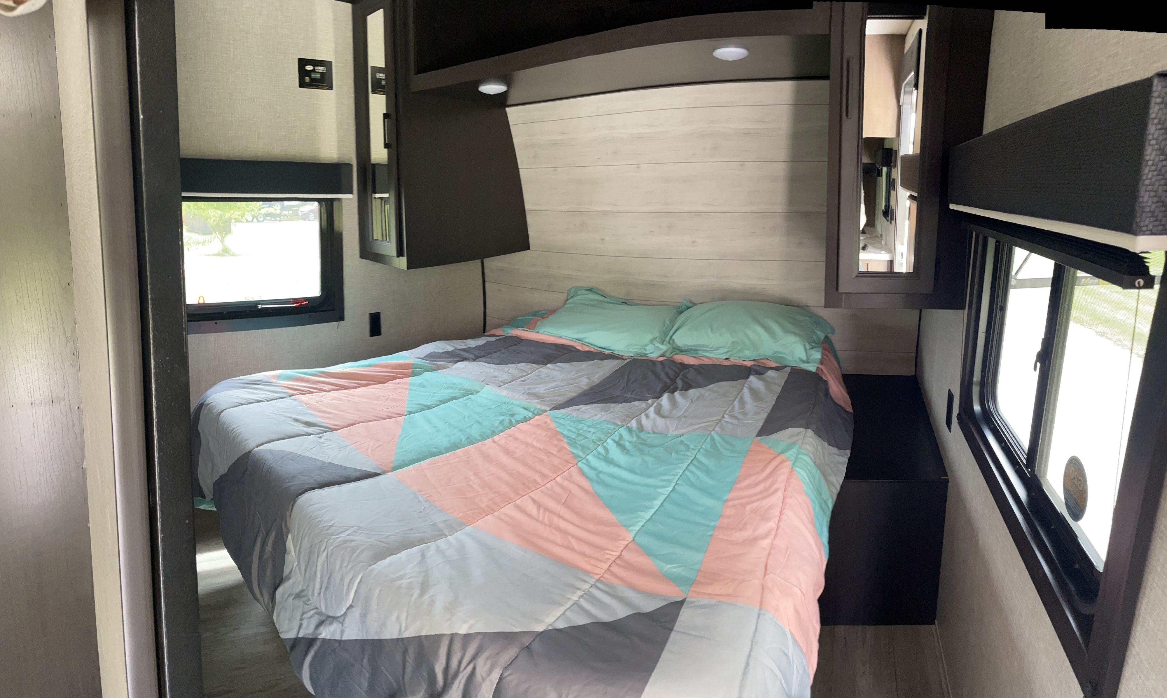 Comfortable RV rental bedroom with a bed, teal & pink geometric comforter, overhead storage, and windows. Ideal for travel.. Jayco Jay Flight 2023
