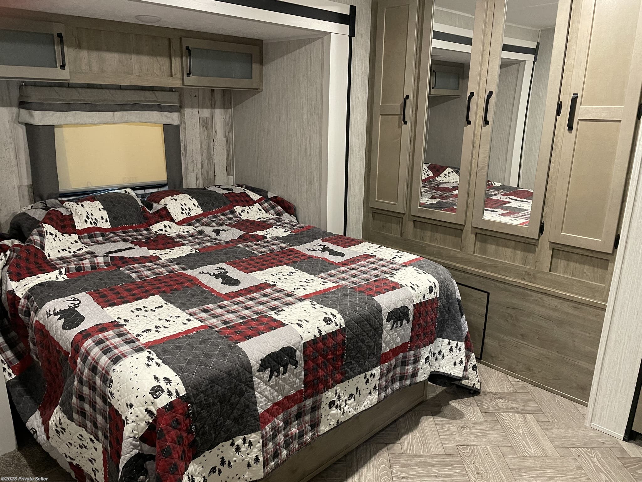 Cozy RV rental bedroom featuring a rustic plaid quilt, mirrored closet, overhead. Forest River Palomino Puma 2021