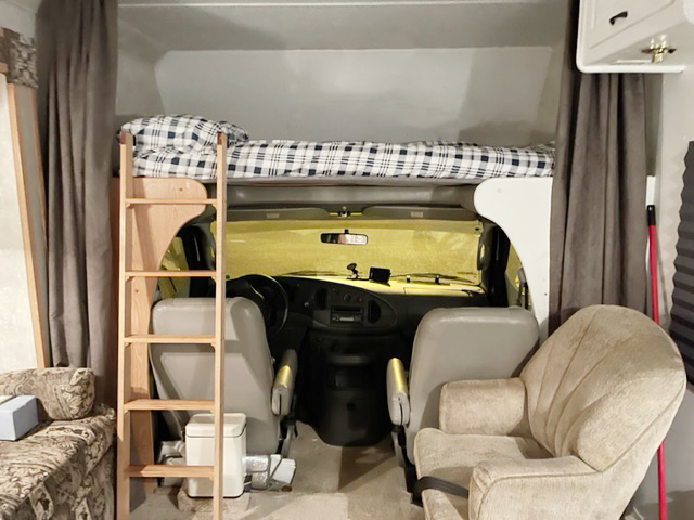 Experience an RV rental! Interior view of a motorhome: cab-over bed with ladder, driver's cockpit, and living area seating.. FORD SUNSEEKER 2004