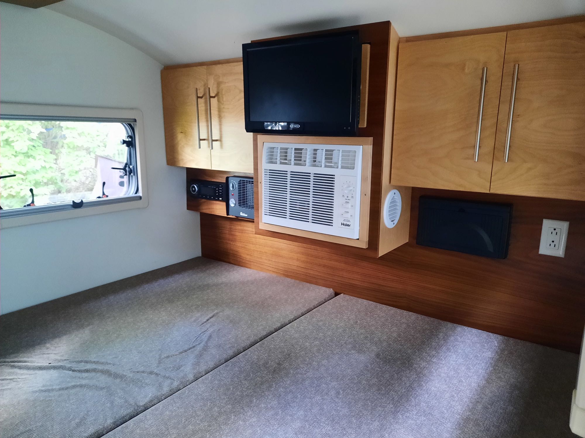 This RV rental interior features a bed, mounted TV, AC unit, and built-in storage.. nuCamp T@G XL 6-Wide Boondock Limited 2020
