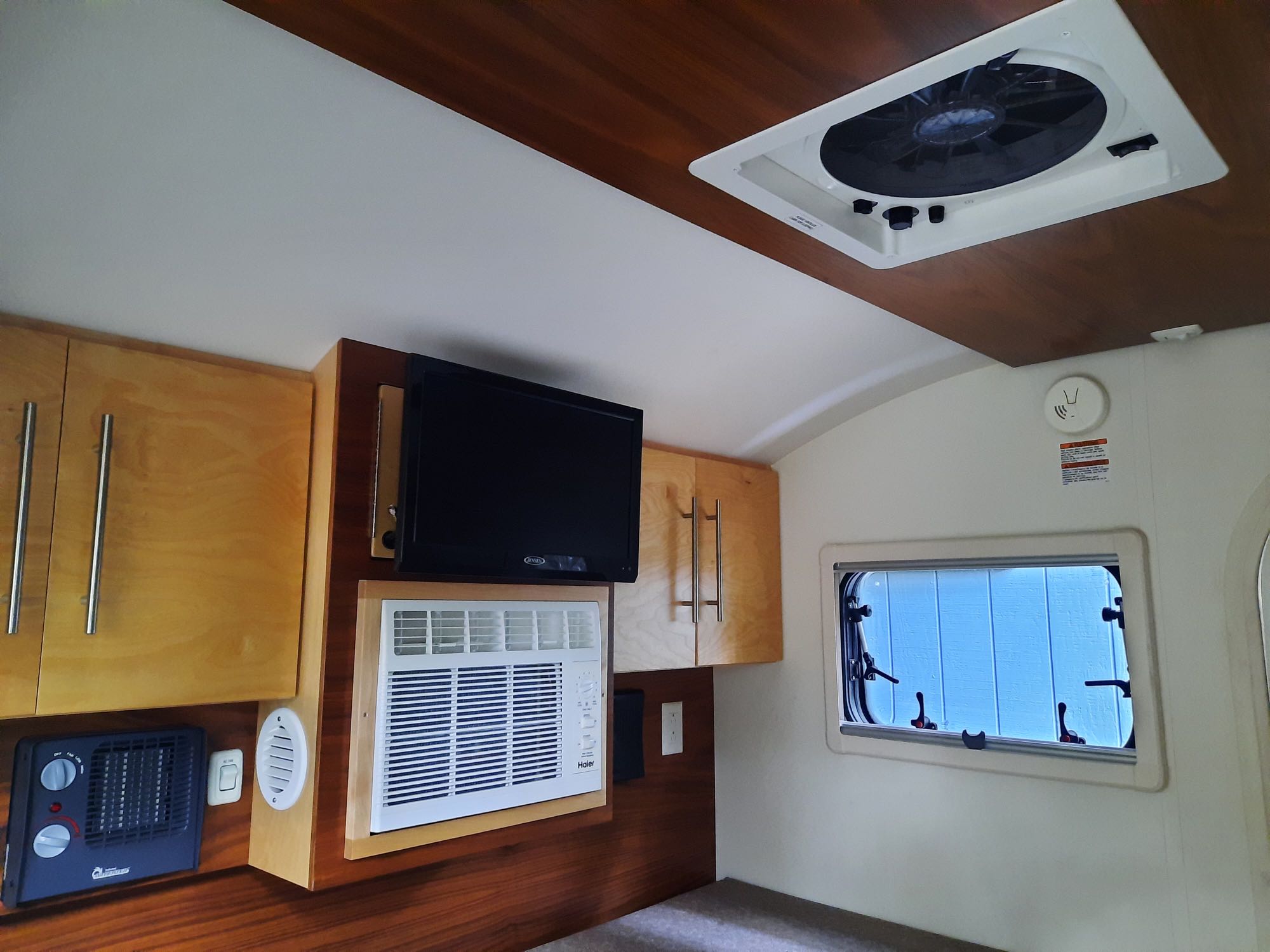 A well-equipped RV rental interior featuring wood cabinets, TV, AC unit, and ceiling fan for your adventure.. nuCamp T@G XL 6-Wide Boondock Limited 2020