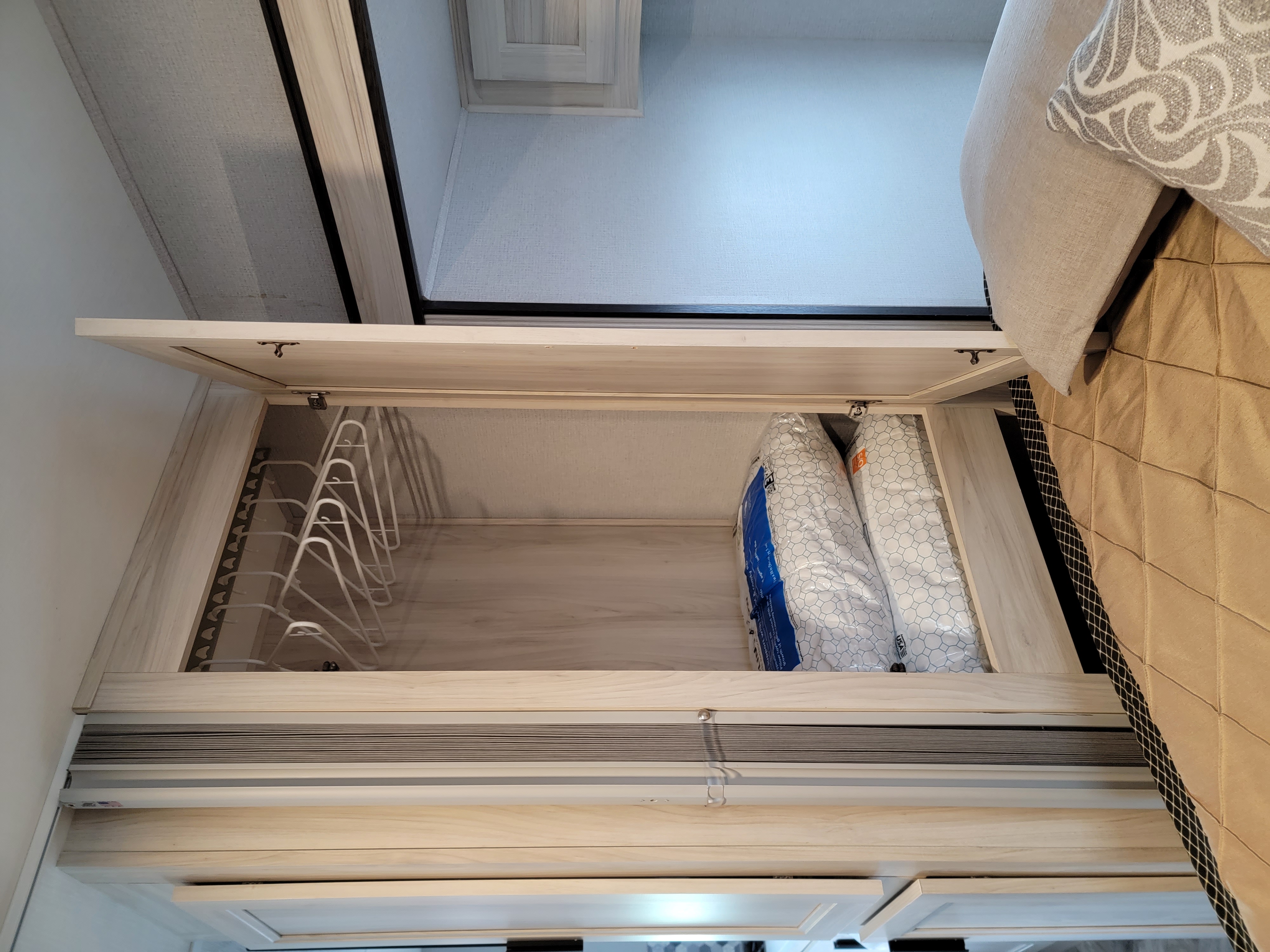 RV rental bedroom: Open overhead cabinet reveals hangers & neatly packed bedding bags.. Forester FRC2551DSLEF 2022