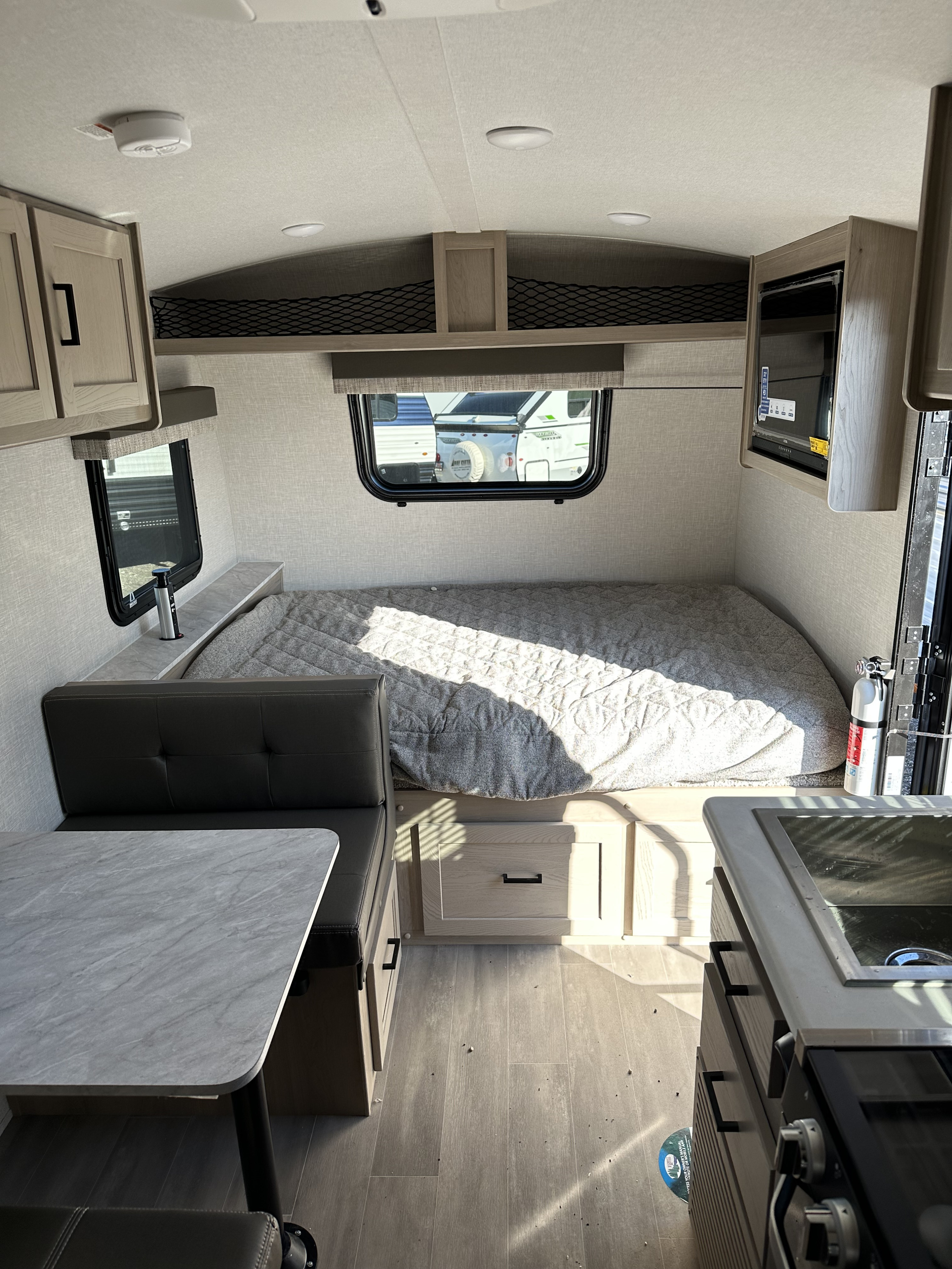 Cozy RV rental interior featuring a comfortable bed, dinette, and kitchenette. Modern design with smart storage & safety features.. Forest River Flagstaff E-Pro 2023