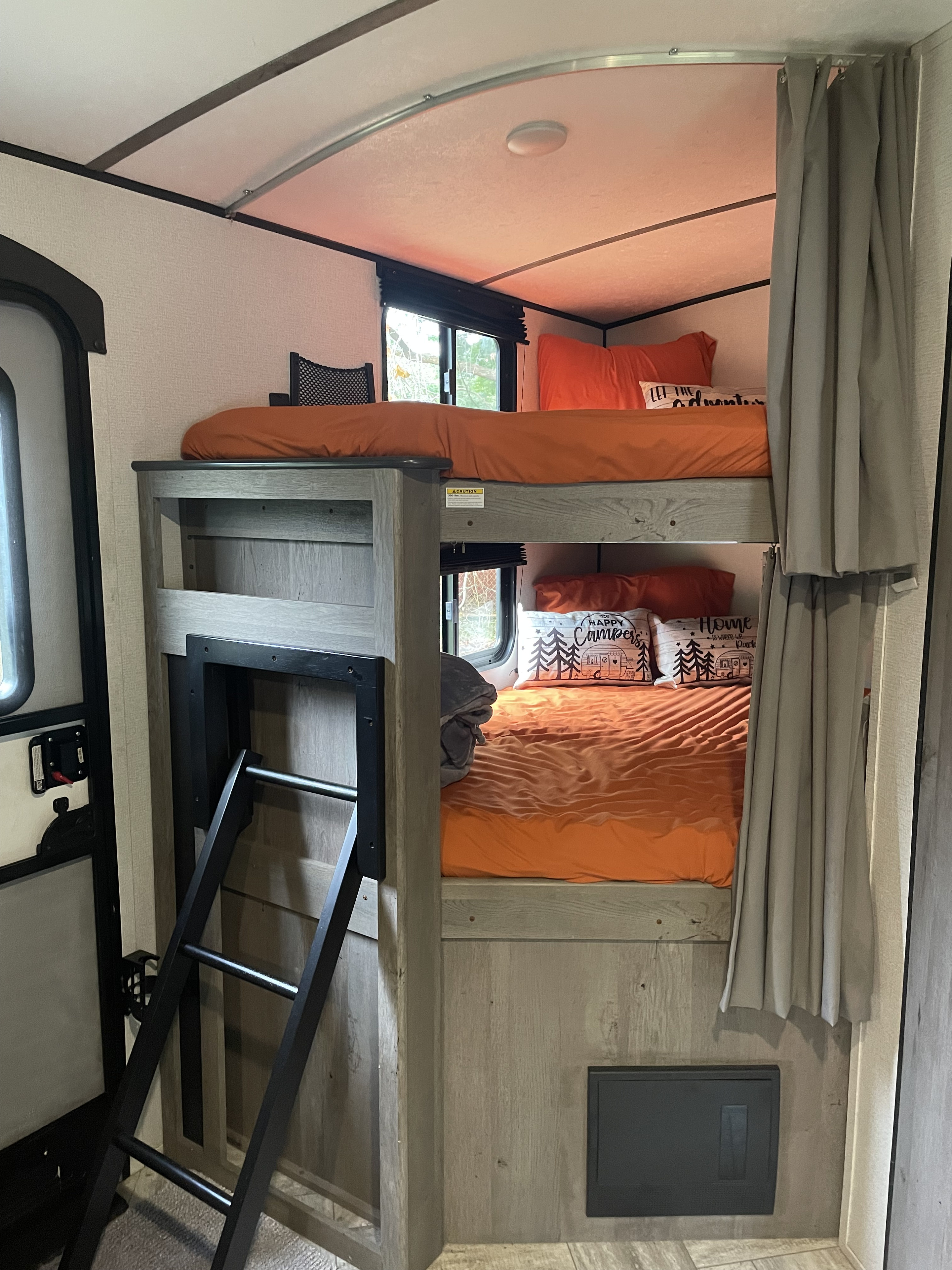RV rental bunk beds with a ladder & orange bedding. A cozy sleeping area for your next camper adventure.. Keystone RV Springdale 2021