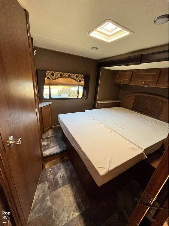 Explore this RV rental bedroom: a cozy interior with a spacious bed, window, overhead storage, and ceiling skylight.. Coachmen Leprechaun 2015