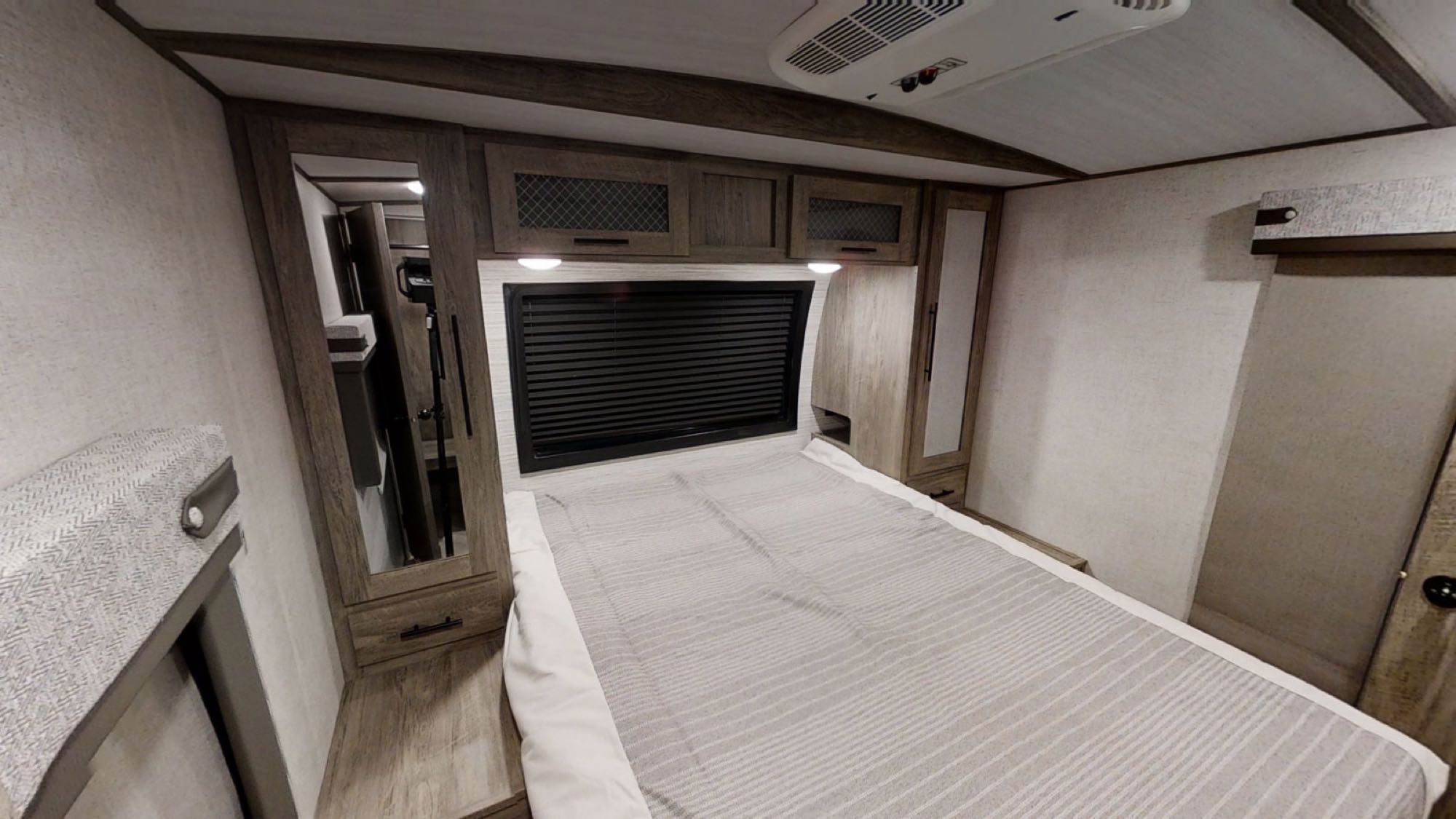 Discover this cozy RV rental bedroom, featuring a comfortable bed, overhead cabinets, and AC unit.. Forest River Wildwood Heritage Glen 2021