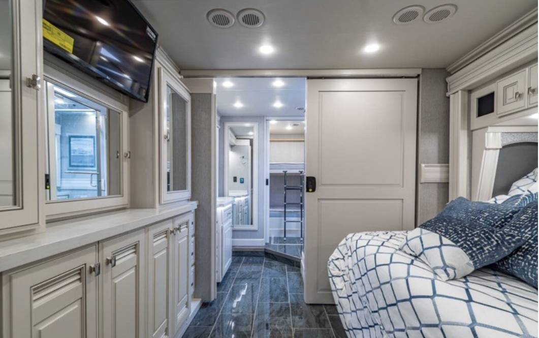 Spacious RV rental interior: Bedroom with sliding door, leading to a hallway with bunk beds and bathroom.. Fleetwood Discovery LXE 2023