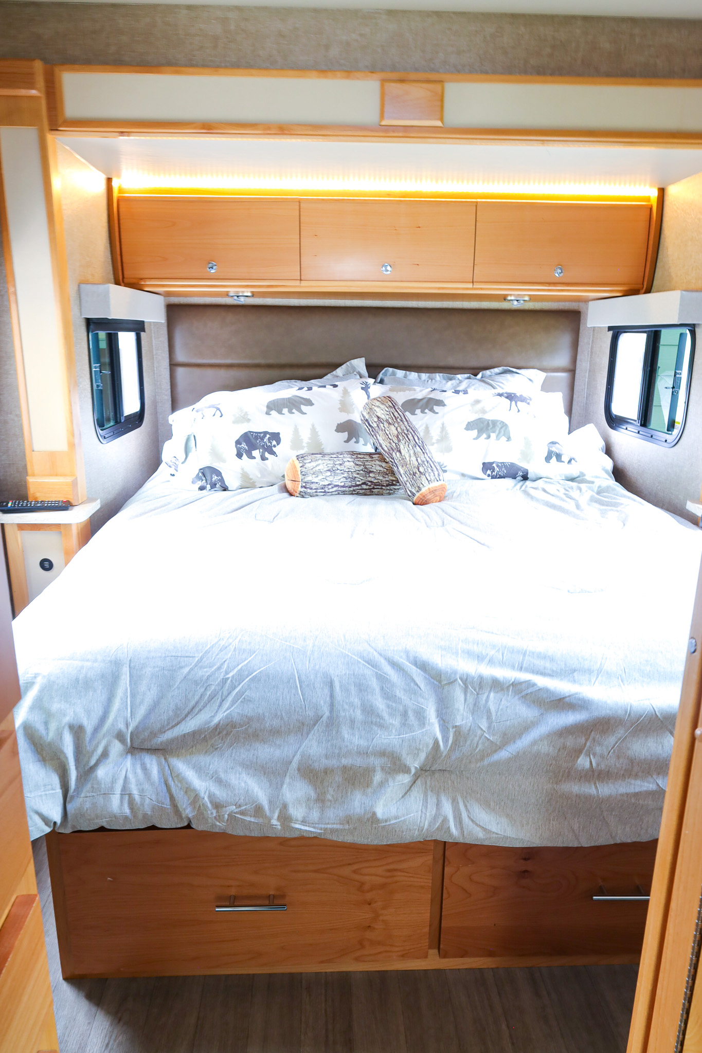 This RV rental bedroom offers a comfortable bed with bear-themed pillows, overhead cabinets, and ambient lighting.. Wayfarer Wayfarer Motorhome 2017