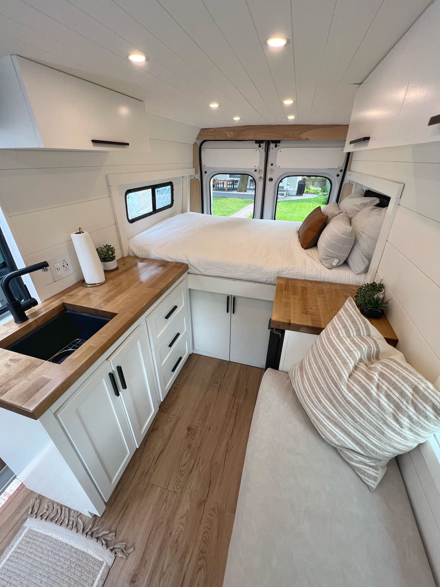 Bright RV rental interior showcasing a modern camper van conversion with a rear bed, compact kitchen, and lounge seat.. Ram Promaster 2500 2016