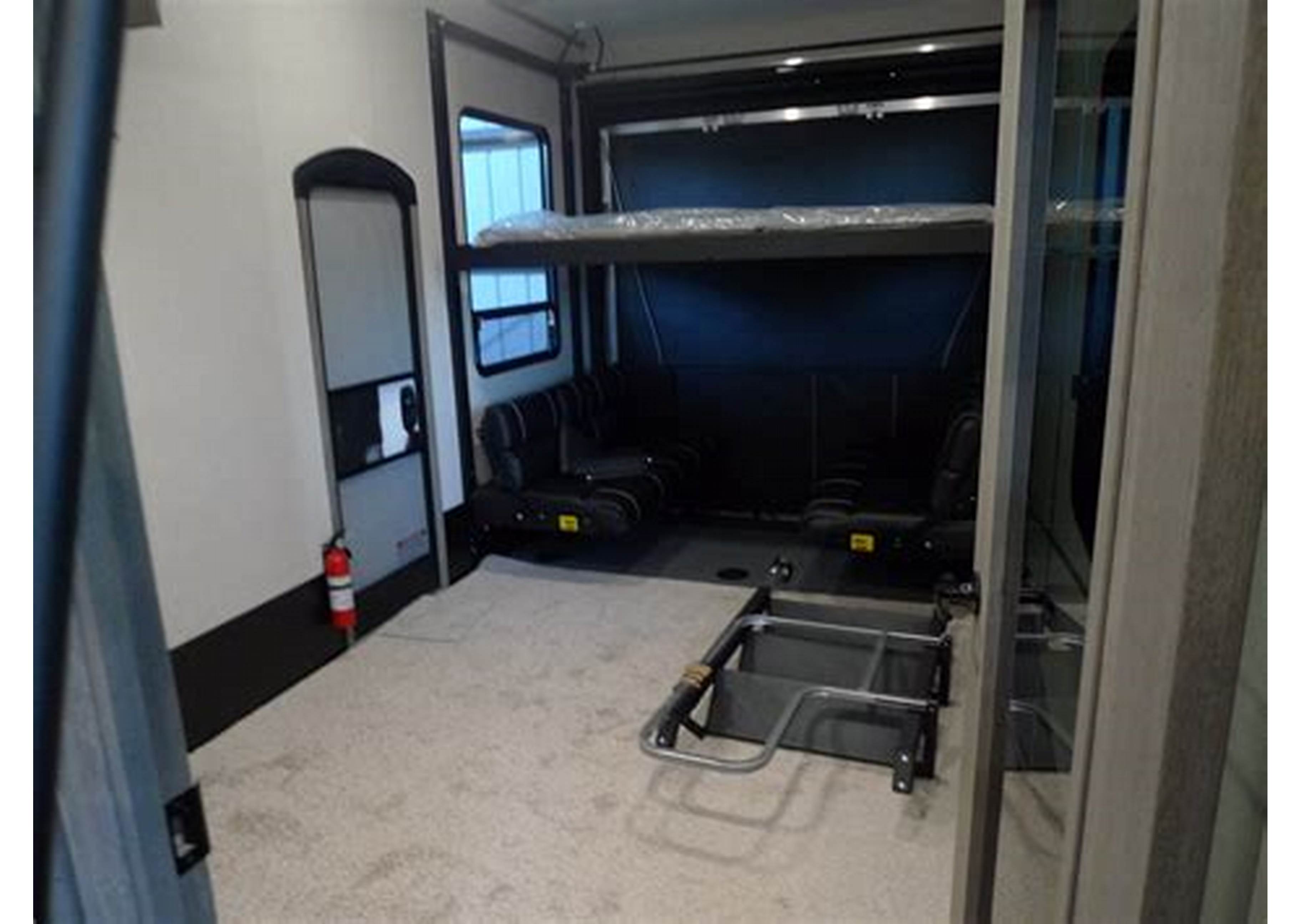 Interior of an **rv rental**: multi-functional space with a drop-down bunk bed, foldable seating, and carpeted floor area.. Keystone Carbon 2021
