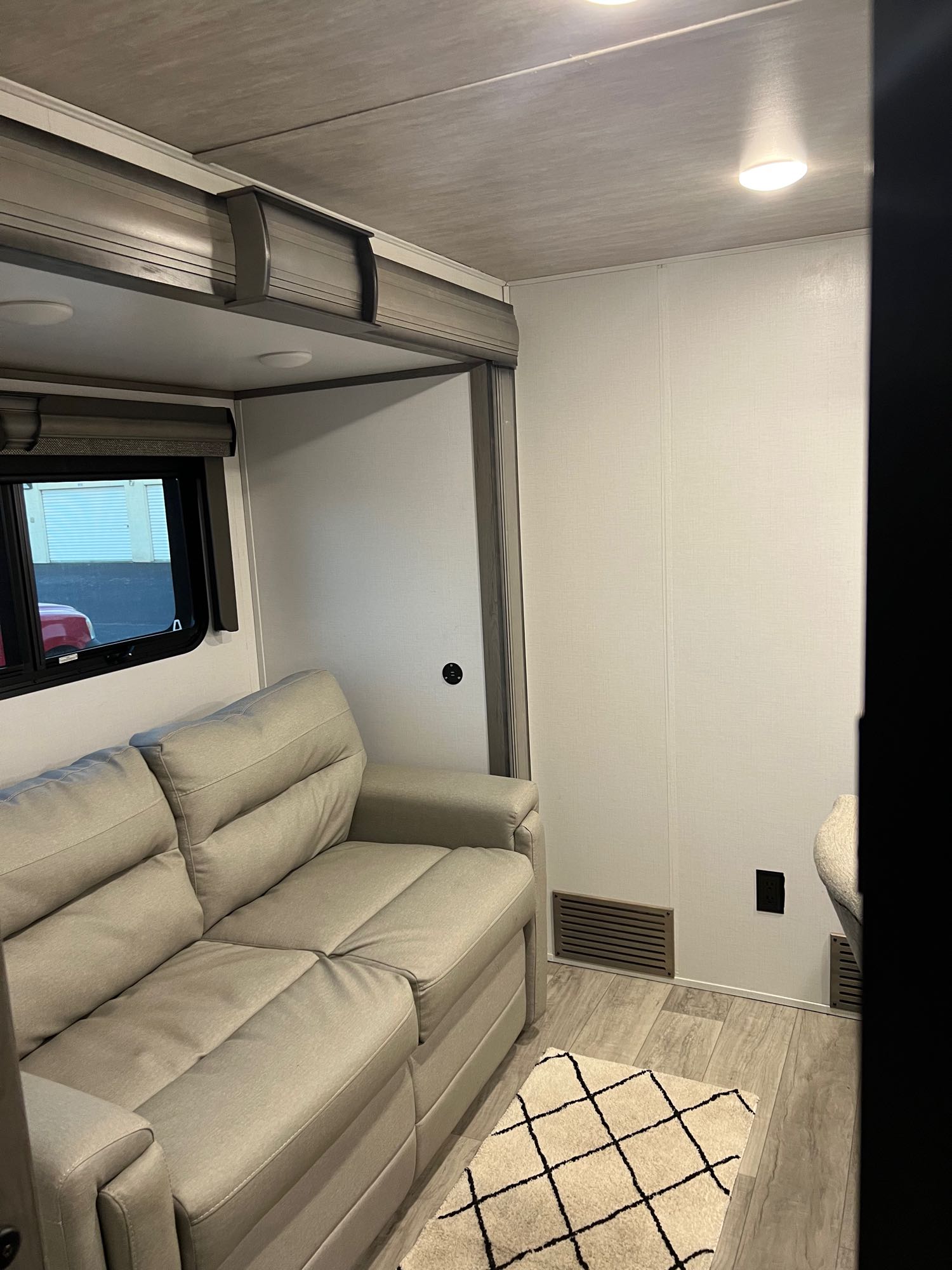 Modern RV rental interior with a light-colored sofa, window, and clean decor, offering a comfortable living space.. Keystone RV Montana 2022
