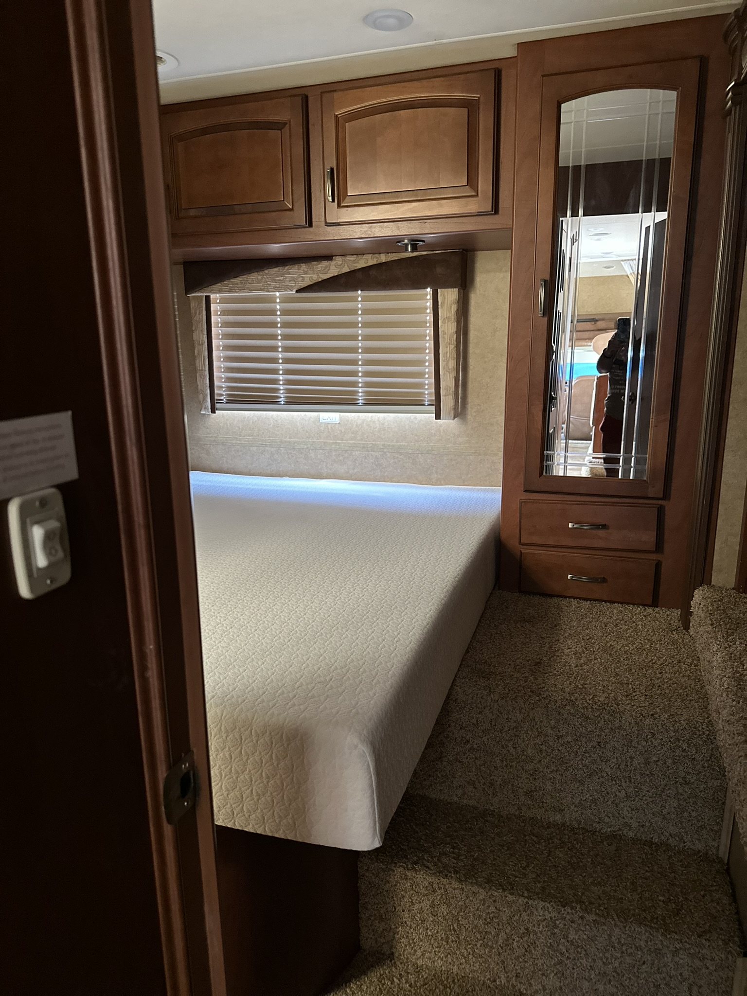 RV rental bedroom: cozy space with white bed, overhead wooden cabinets, and mirrored wardrobe.. Jayco Greyhawk 2014