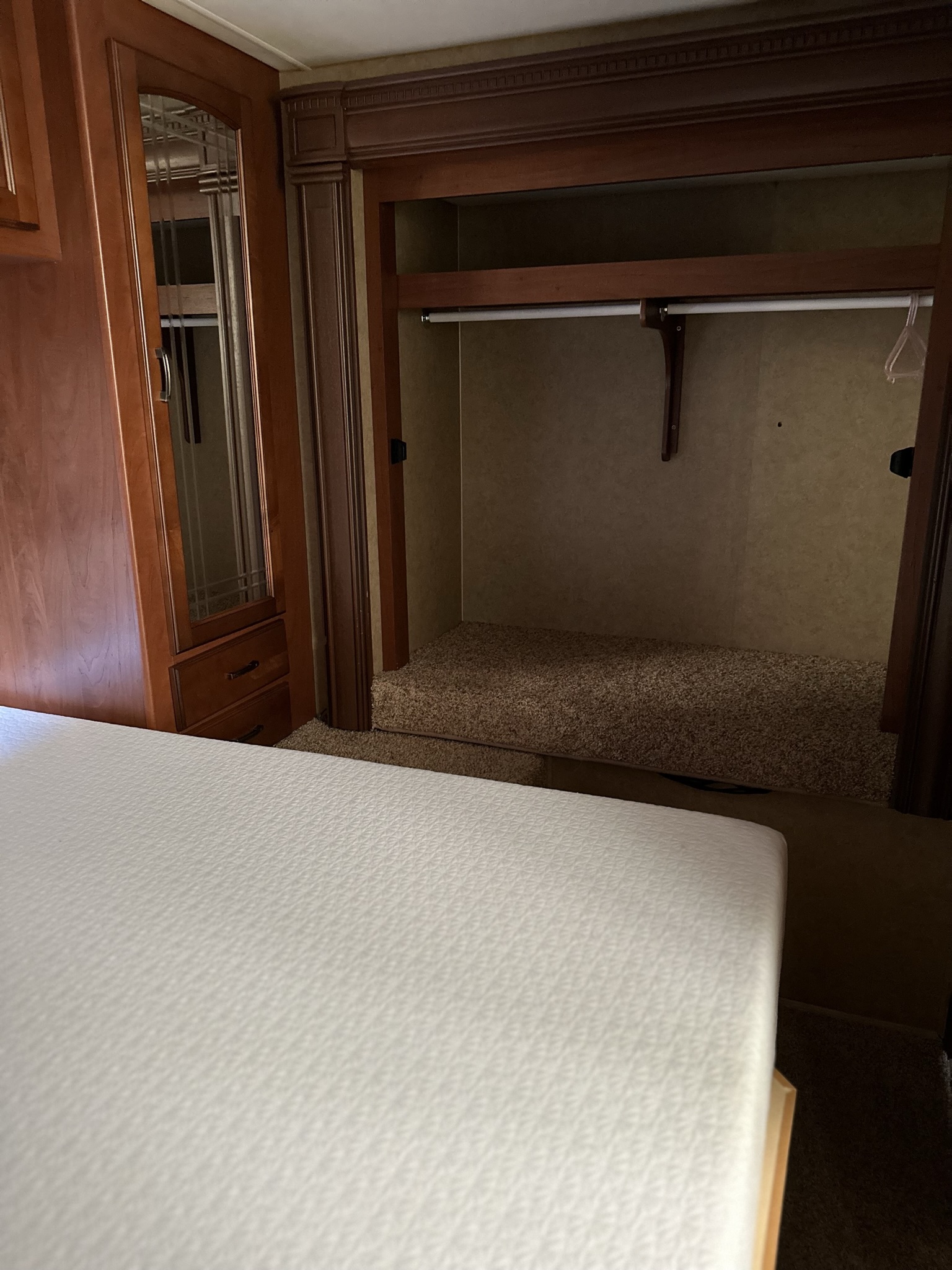 Inside an RV rental: a neat bedroom with a white mattress, mirrored closet, and ample storage for your journey.. Jayco Greyhawk 2014