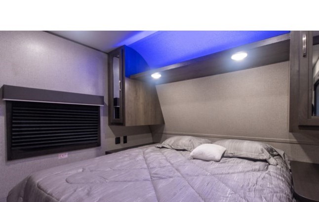 Cozy RV rental bedroom featuring a comfortable bed, overhead storage, and modern blue accent lighting.. Jayco Jay Flight SLX 2022