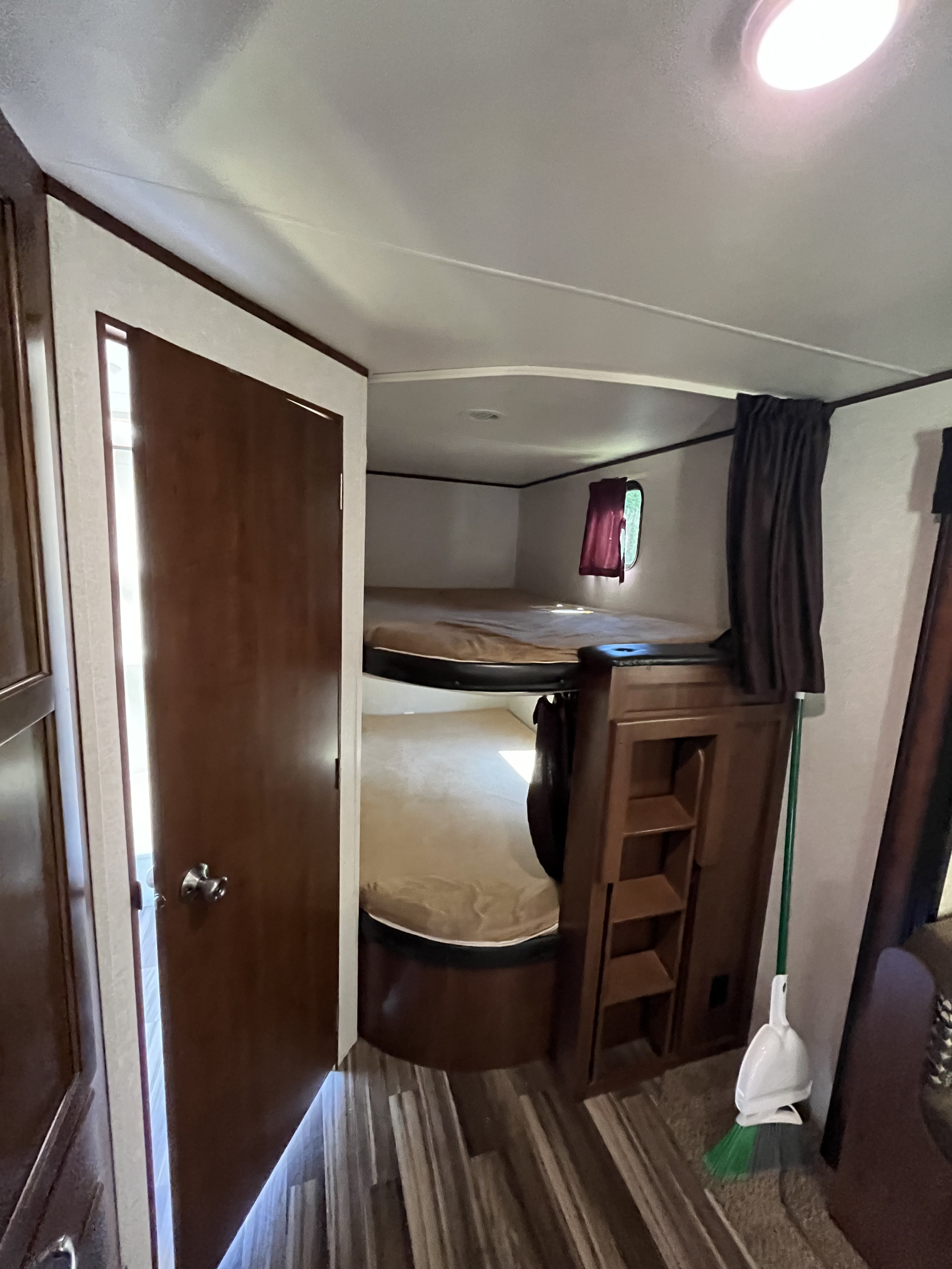 RV rental interior displaying a bunk bed area with two mattresses, an open door, and a broom/dustpan.. Jayco Jay Flight SLX 2017