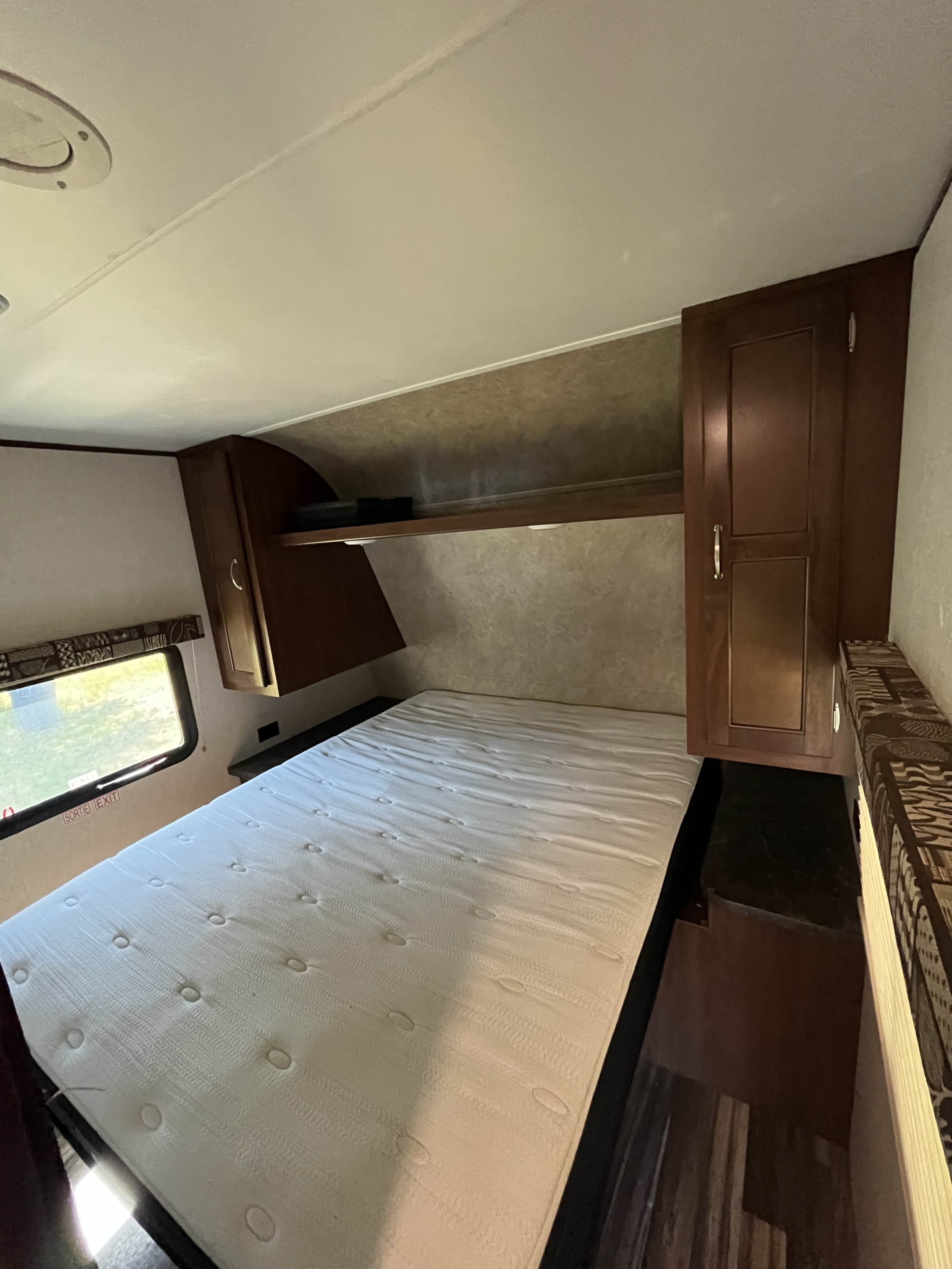 RV rental: Bedroom interior featuring a spacious mattress, overhead cabinets, and window for comfortable travel.. Jayco Jay Flight SLX 2017