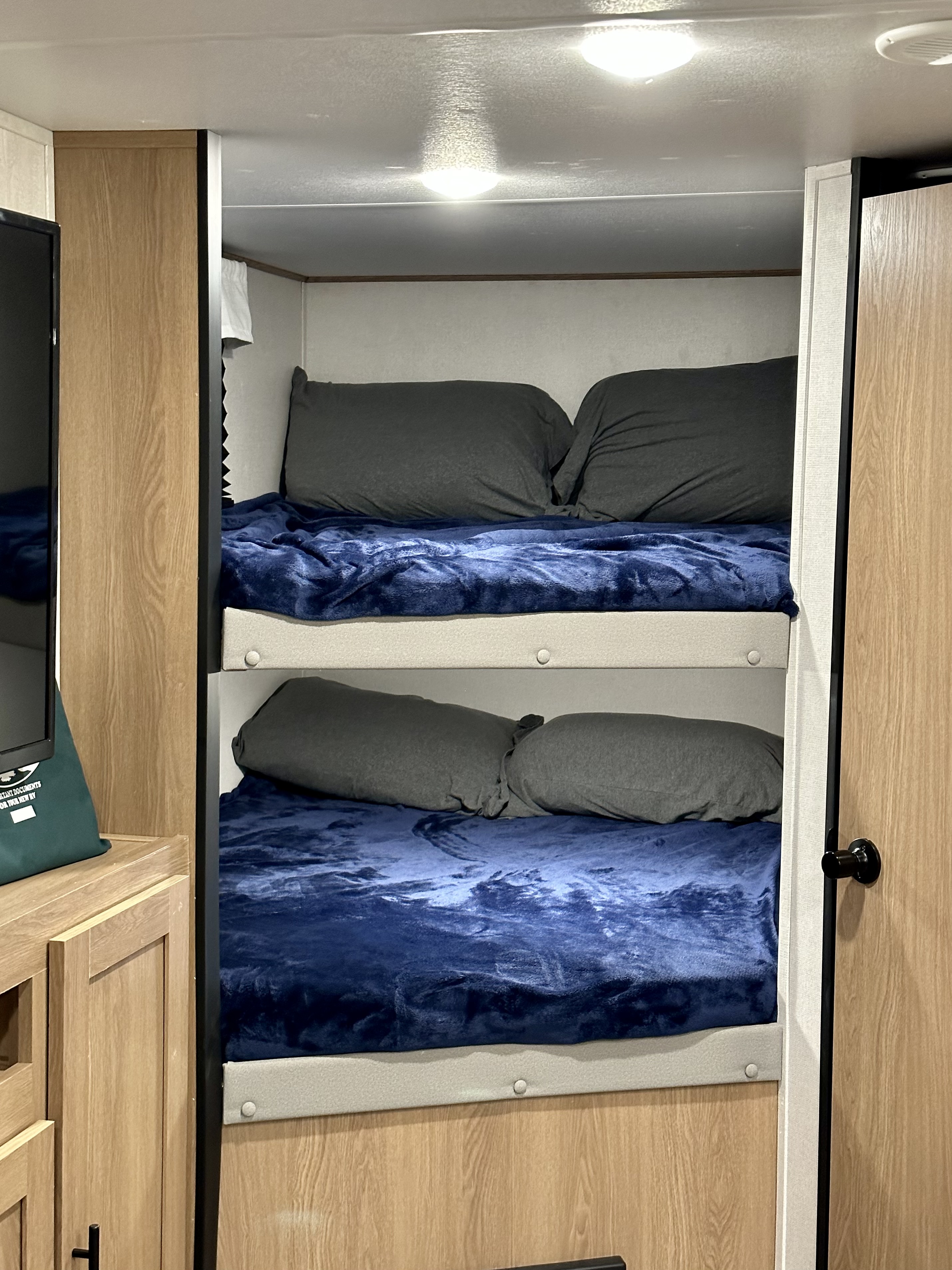 Cozy bunk beds in an RV rental, featuring soft blue blankets and dark pillows, ready for your next adventure.. Prime Time RV Avenger 2022