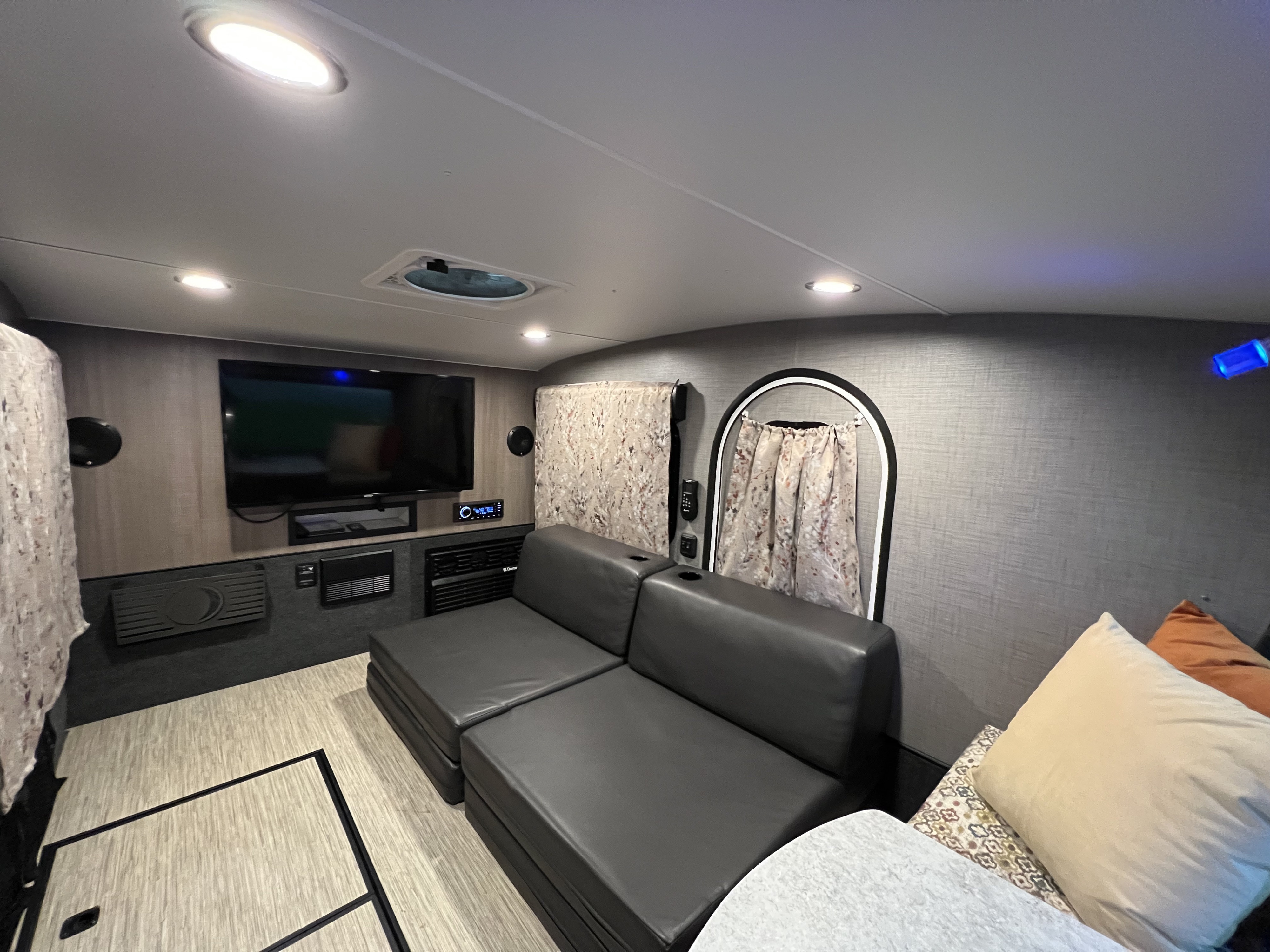 Spacious RV rental interior: view of the living area with a dark gray sectional sofa, wall-mounted TV, and bright lighting.. InTech RV InTech RV Trailer 2018