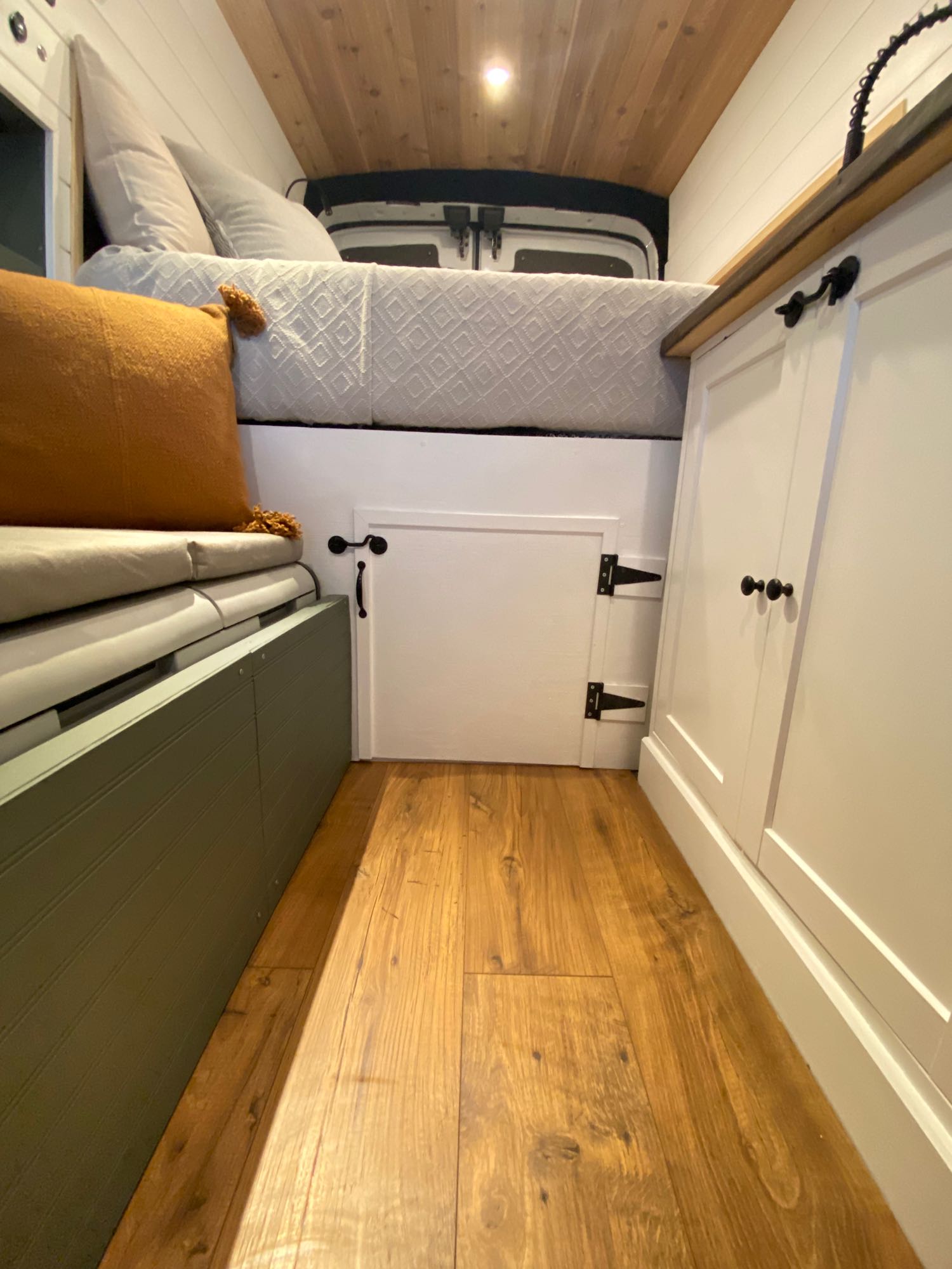 RV rental: View inside a camper van with a cozy bed, green and white storage, wood floors, and ceiling.. Ford Transit custom 2019