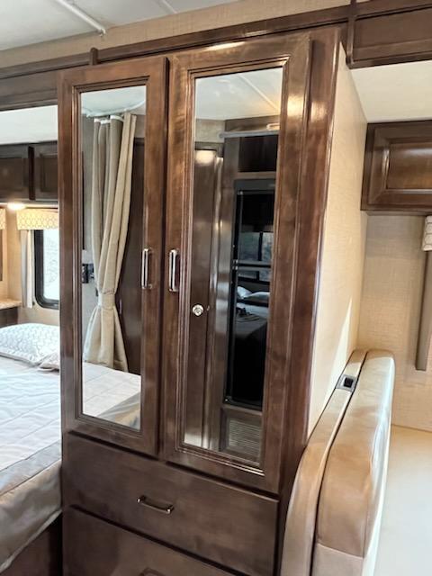 RV rental bedroom: Mirrored wood wardrobe with drawers and a nearby bed provide storage.. Thor Quantum 2020