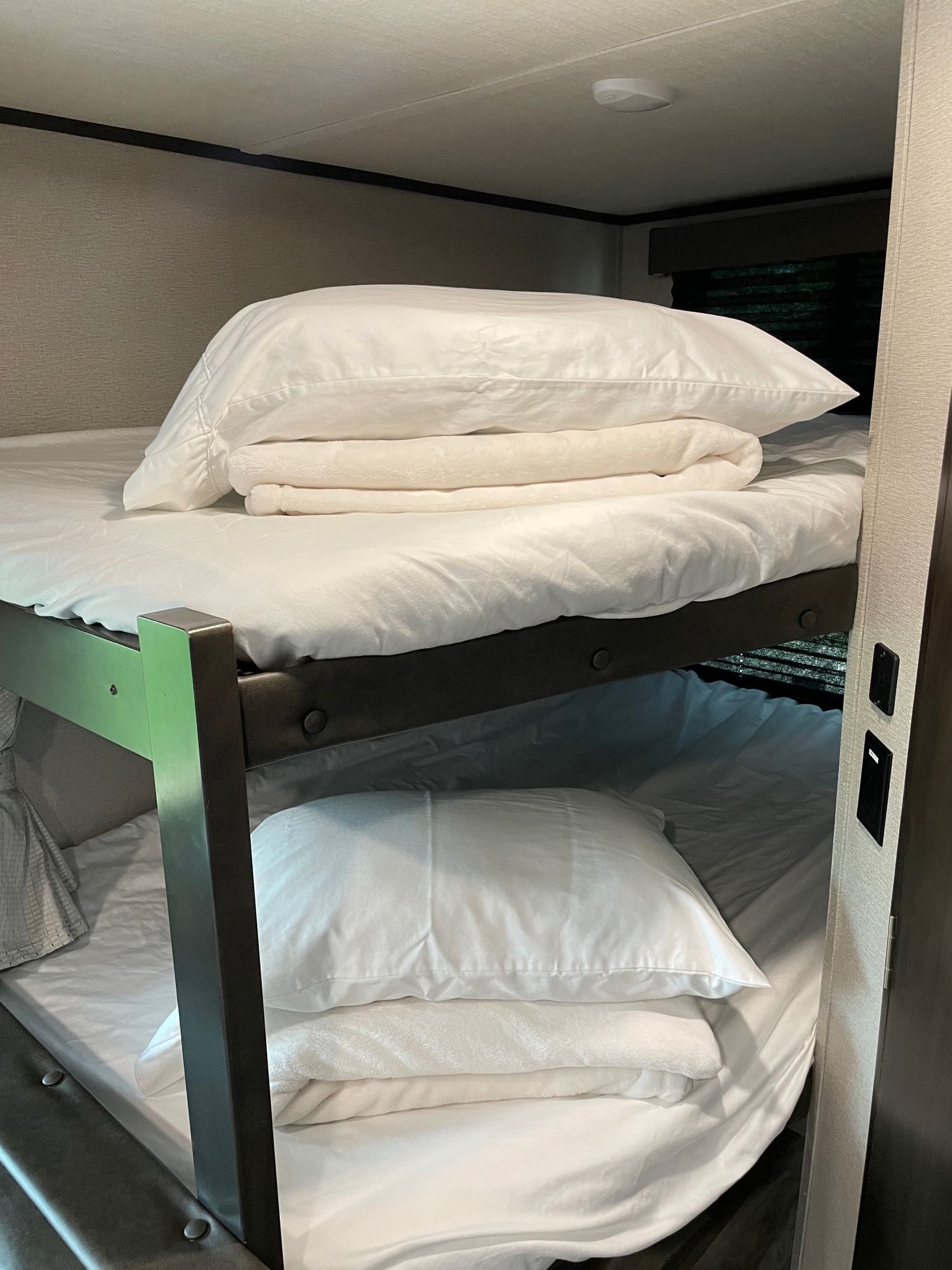 Clean bunk beds with white linens in an RV rental, offering comfortable sleeping space for travel adventures.. Grand Design Transcend 261BH 2022