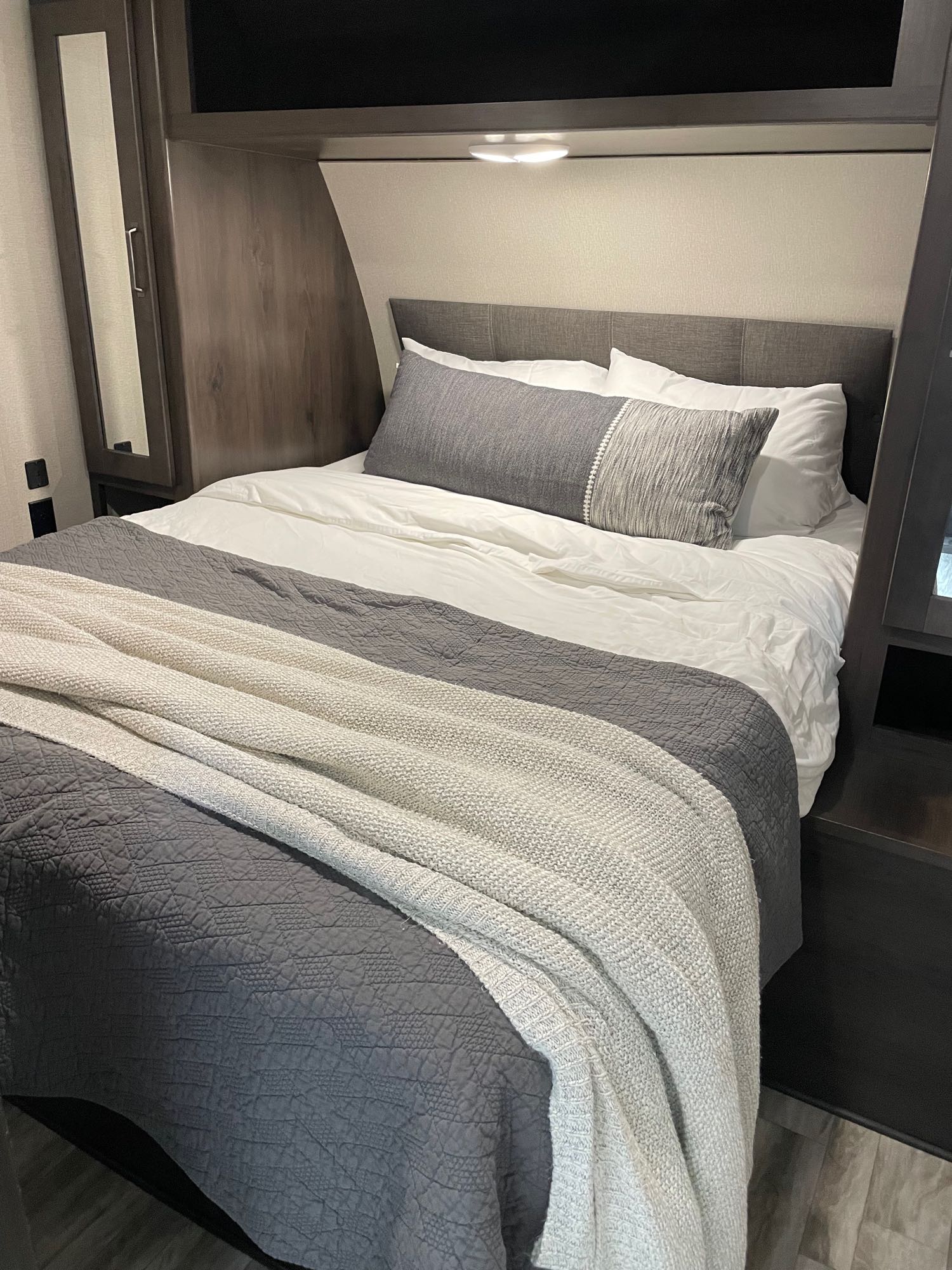 Cozy RV rental bedroom featuring a made bed with white & gray linens, headboard, & built-in storage. Perfect for travel.. Grand Design Transcend 261BH 2022