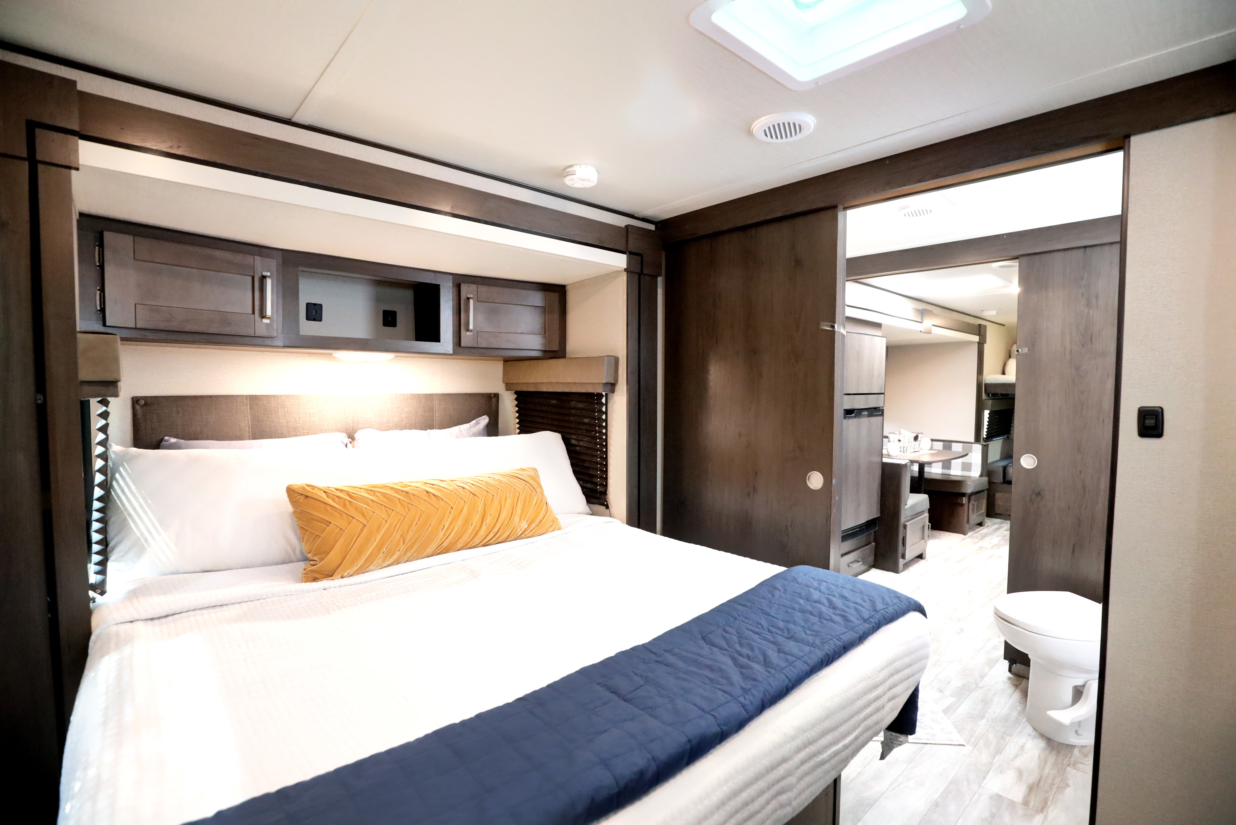 Spacious RV rental bedroom with cozy bed, overhead storage, and sliding door to the living area and bathroom.. Grand Design Transcend Xplor 2022