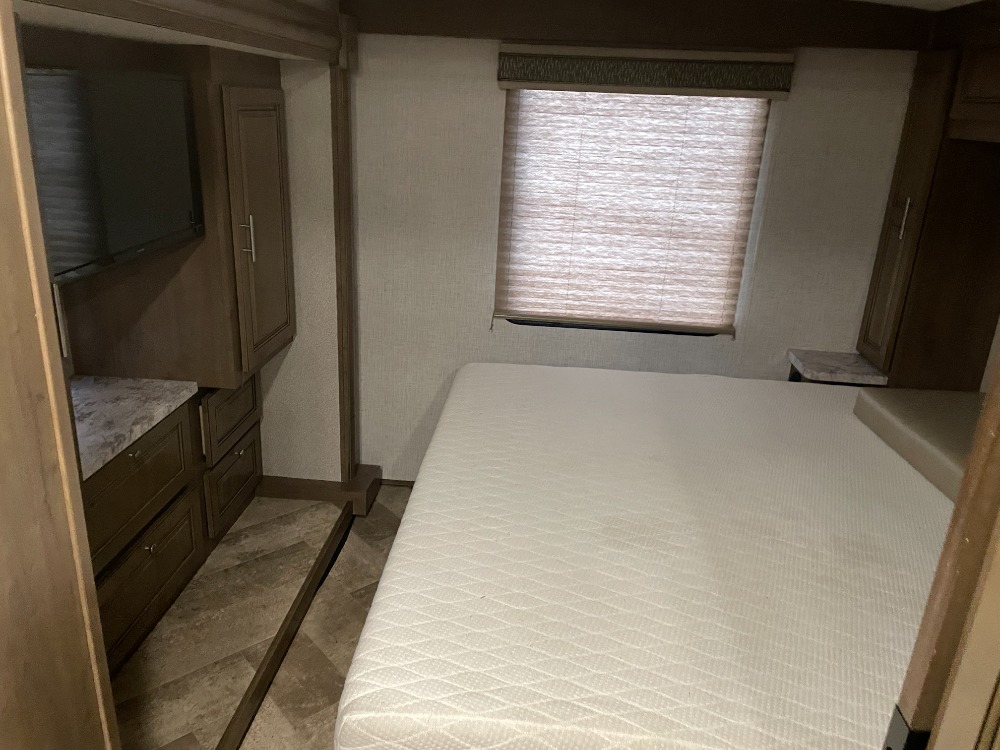 Cozy RV rental bedroom featuring a comfy bed, window, TV, and built-in storage, perfect for travel adventures.. Forest River Georgetown 3 Series 33b 2020