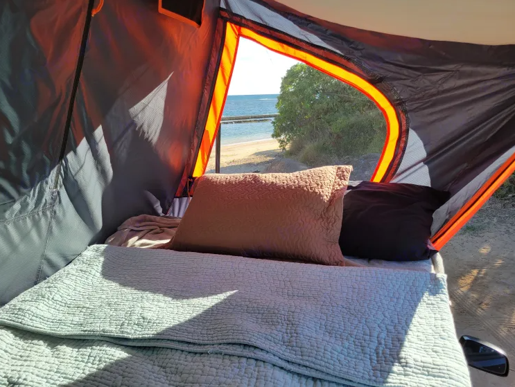 Cozy RV rental bed with a view of the beach and ocean. Perfect for scenic camping trips.. Nissan Xterra 4x4 2012